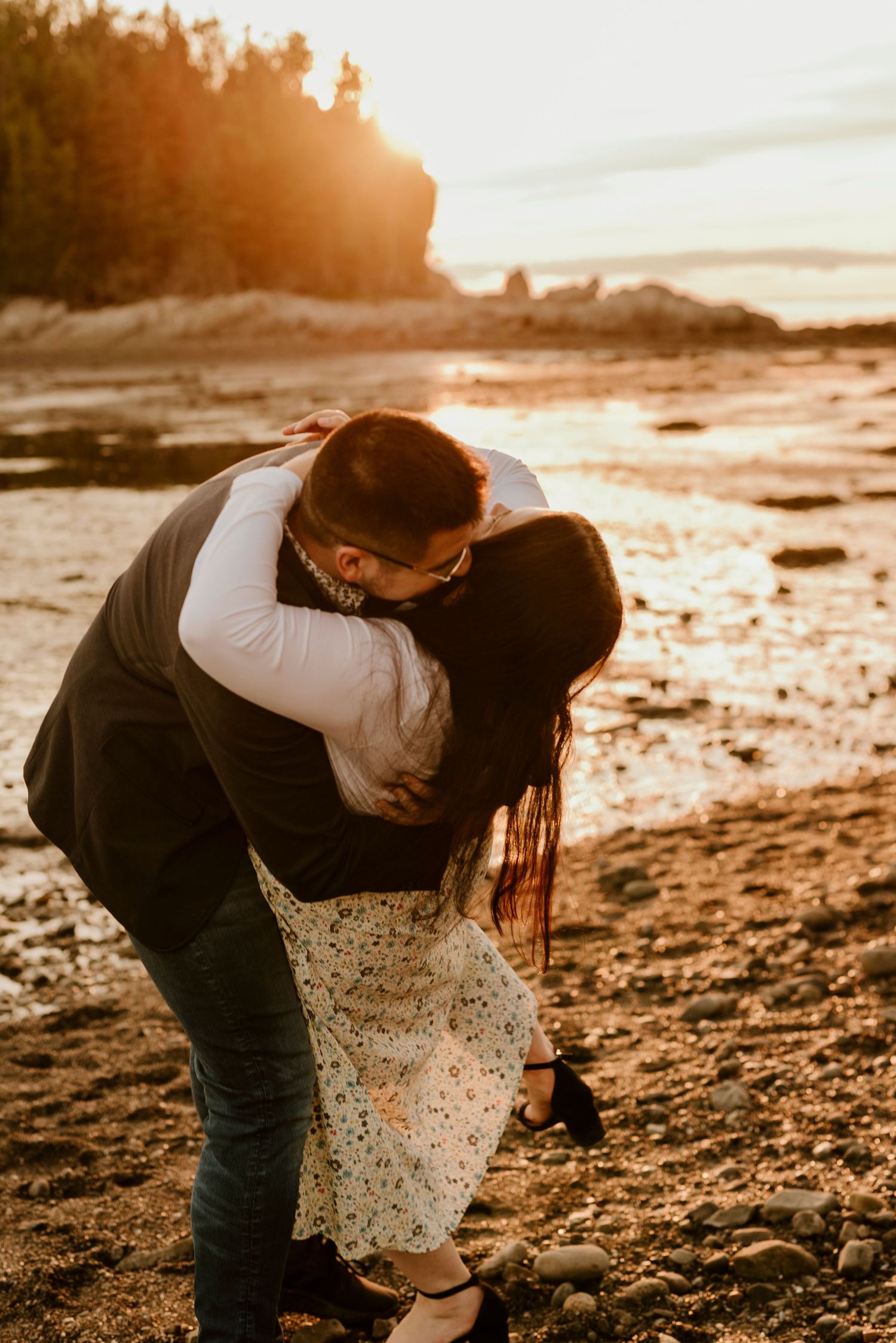 Intimate embrace between couple on beach during golden sunset.