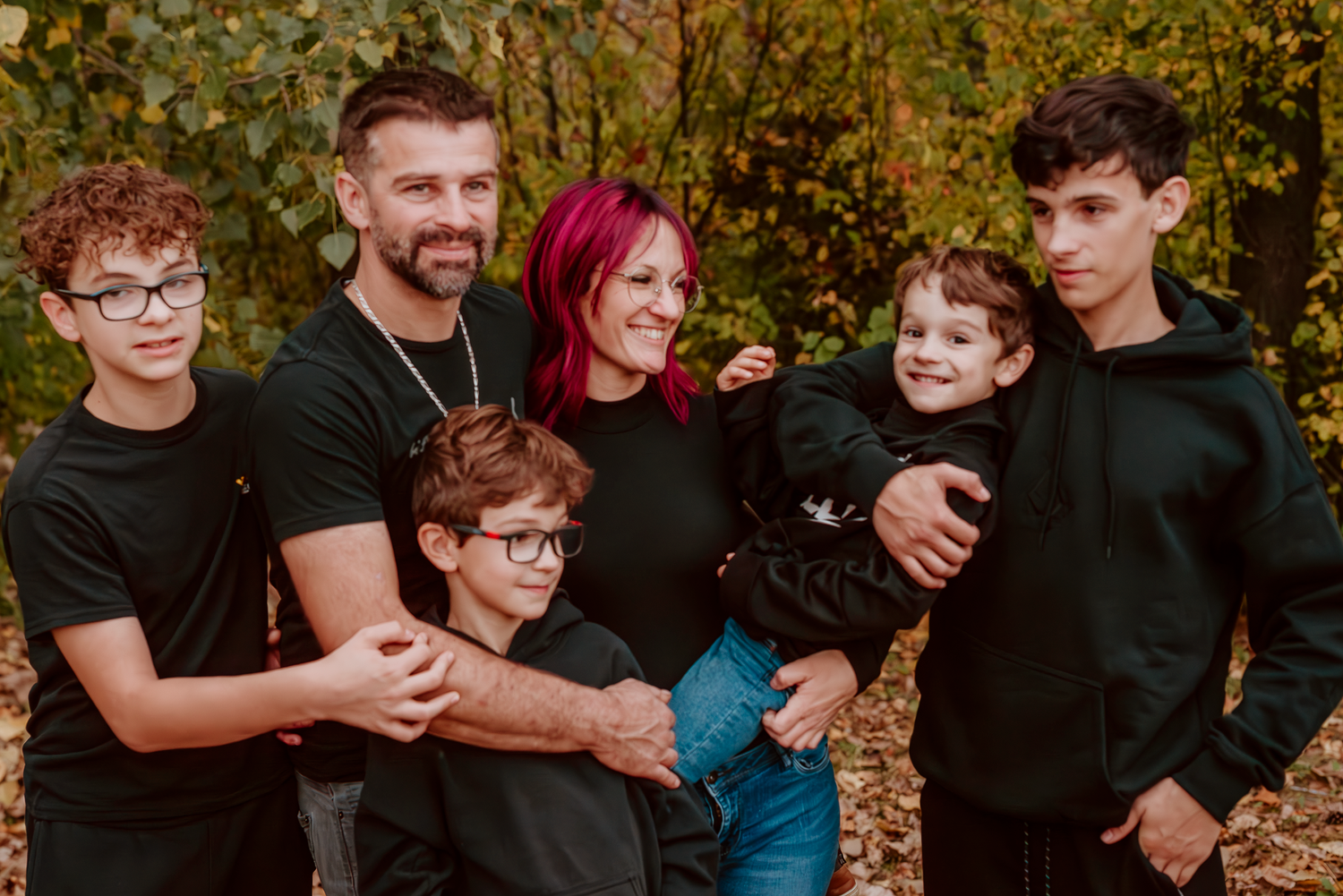 Une famille de six, heureuse et aimante, pose dans un décor automnal et chaleureux.