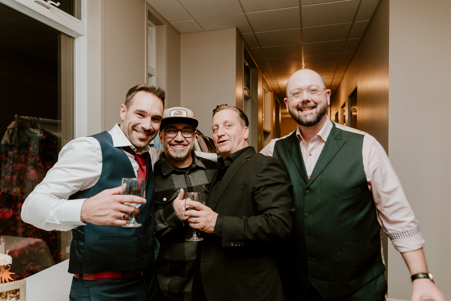 Group of men in formal attire toast with drinks at indoor celebration.