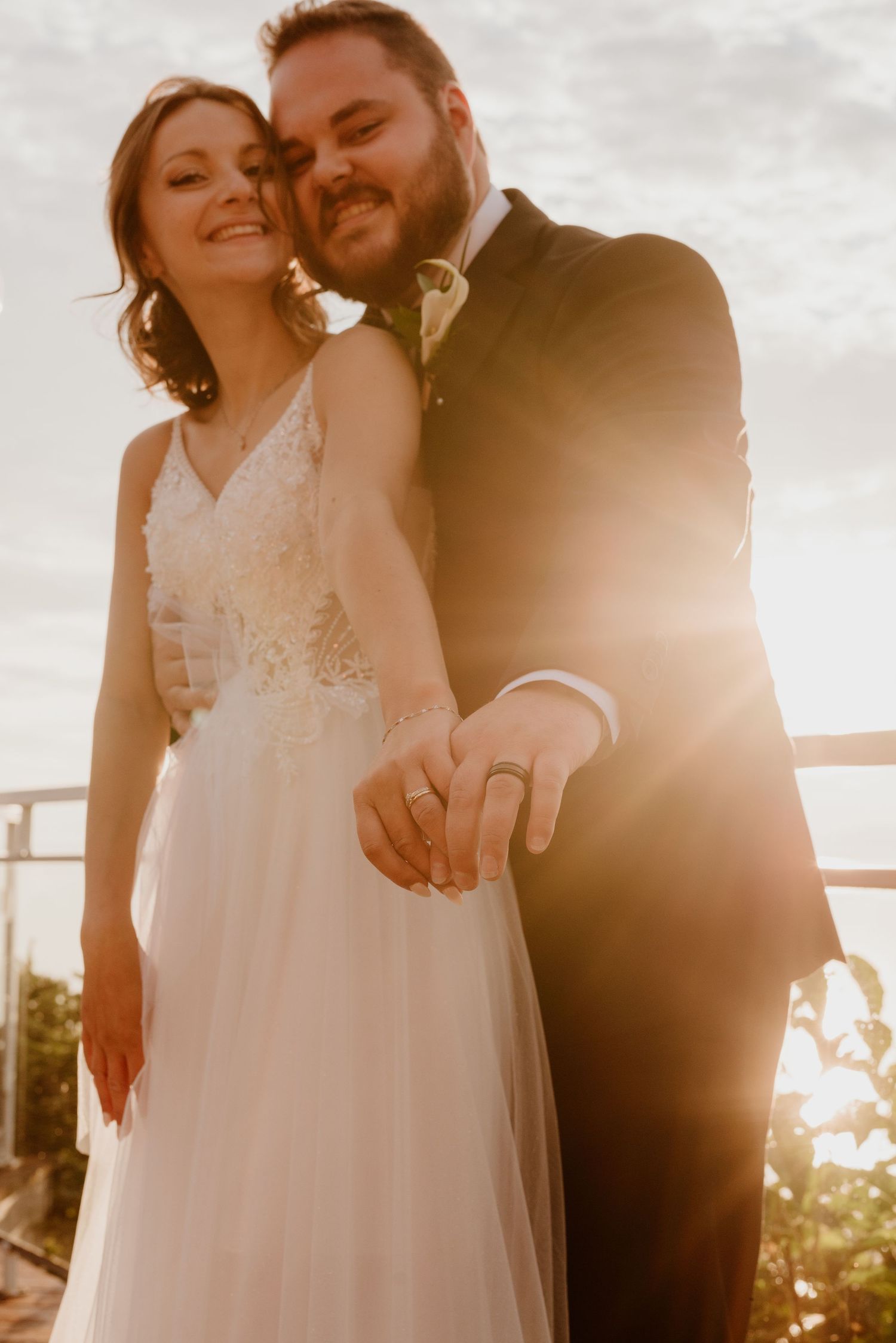 Newlyweds embrace during golden hour on their wedding day with beautiful sunset lighting.