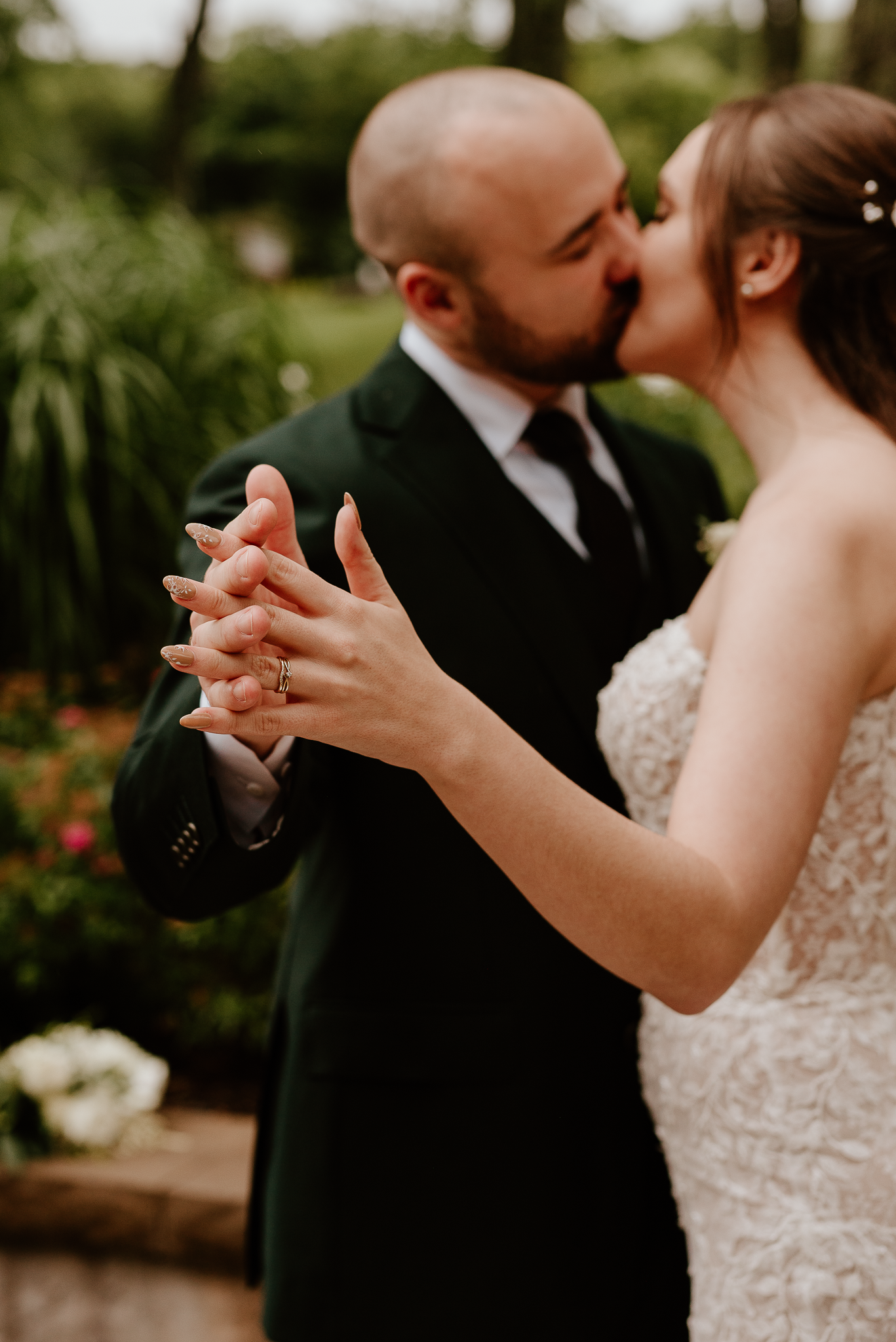 Close-up of newlyweds sharing a kiss while holding hands during their first dance.