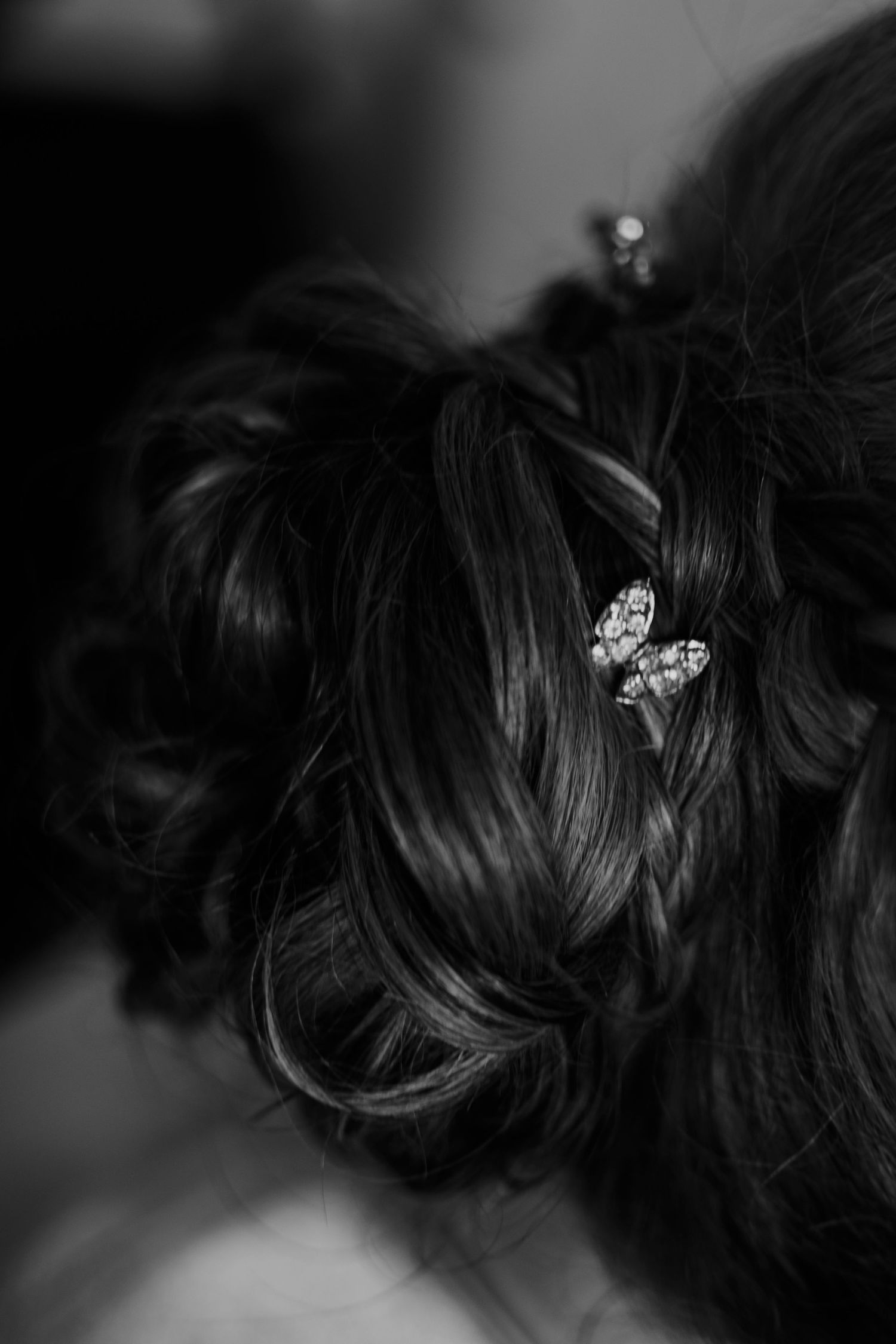 Close-up black and white photo of an elegant bridal updo hairstyle with crystal hair accessories.