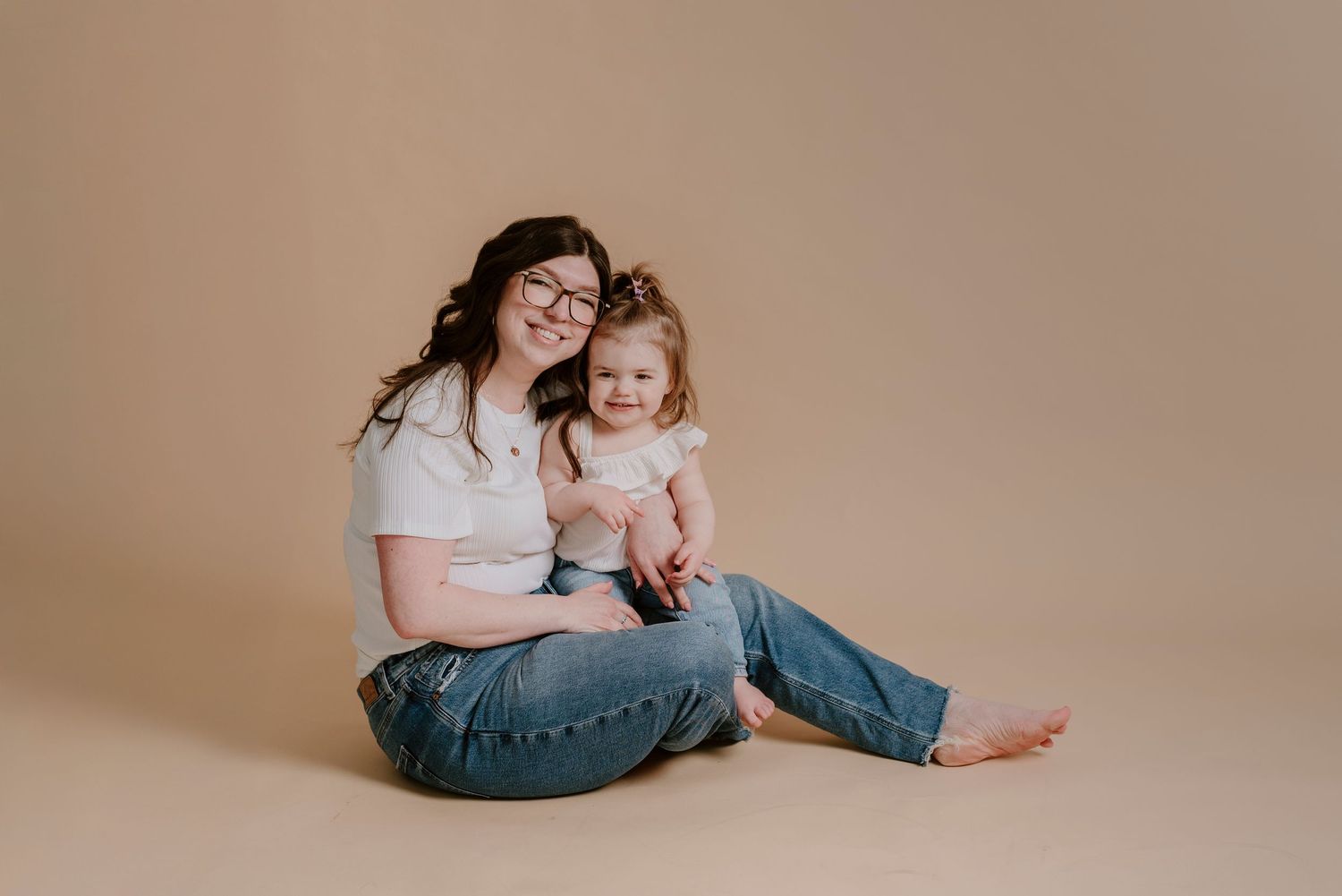 Assises par terre, une mère et son enfant s'enlacent dans un décor minimaliste.