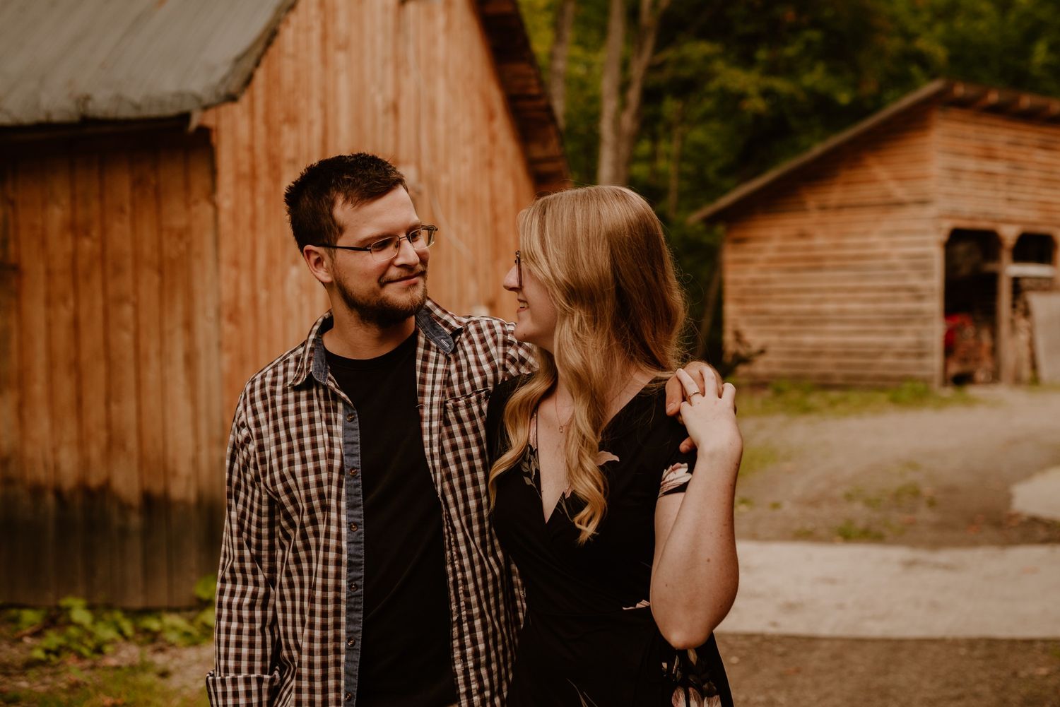 Romantic moment between couple by rustic wooden barn in countryside setting.
