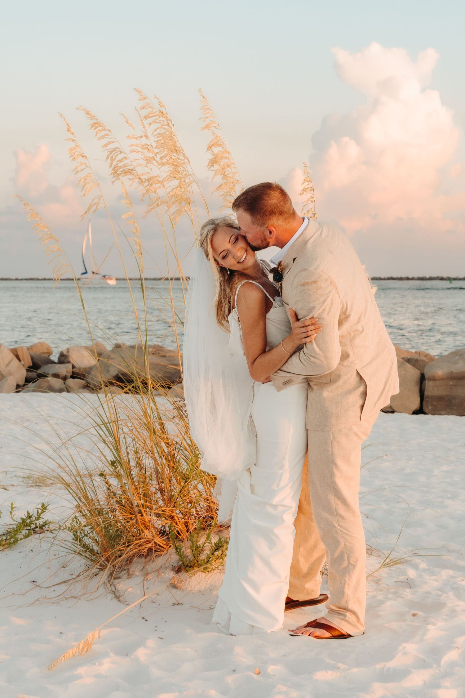 Romantic beach wedding photoshoot at sunset with sea oats and white sand.