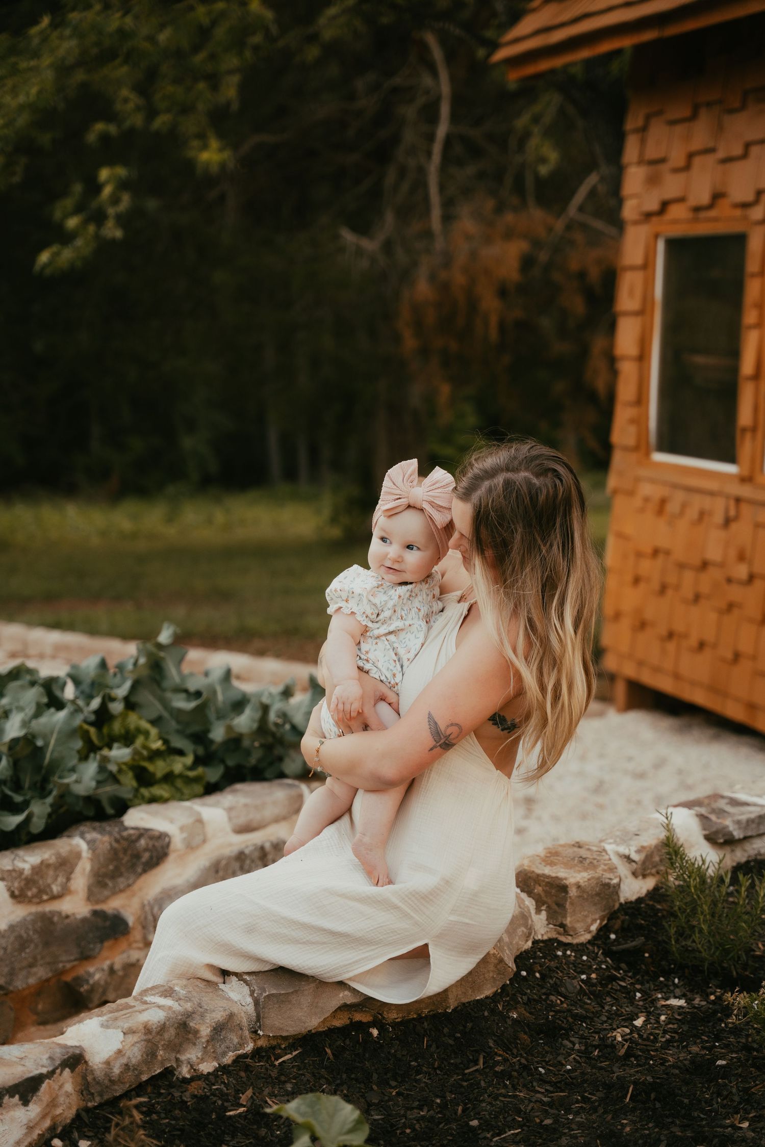Mother and baby share tender moments together in a rustic outdoor setting at sunset.
