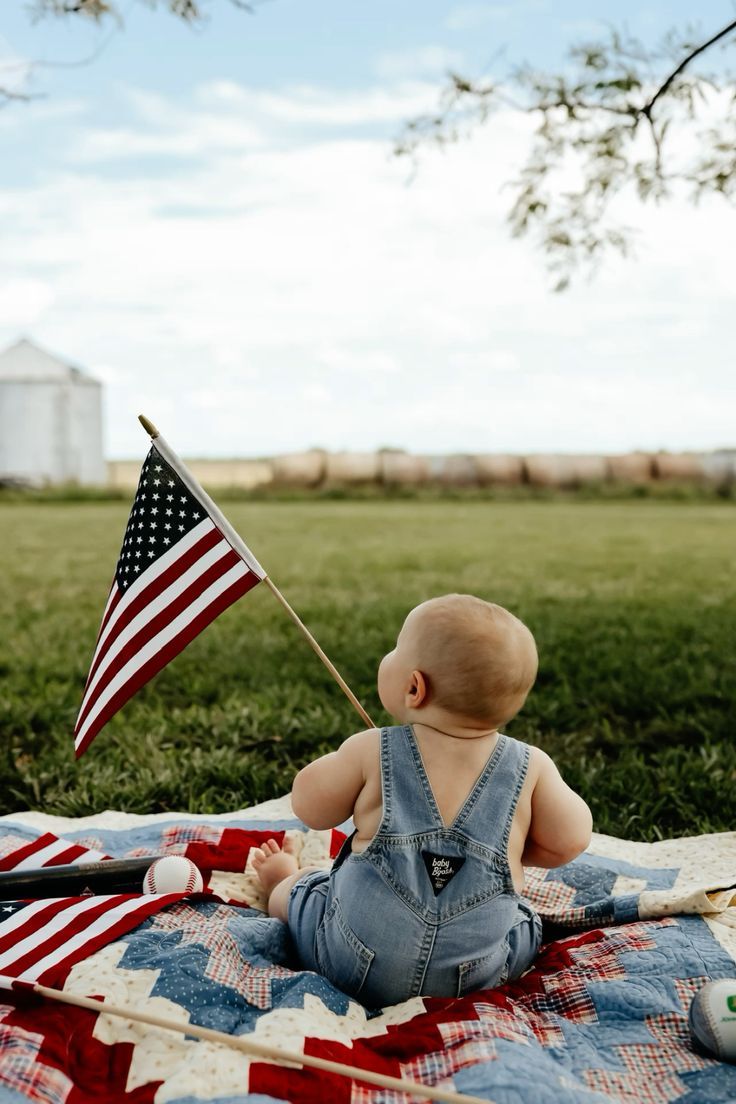 American flags and a patchwork quilt laid out on green grass under a bright blue sky.