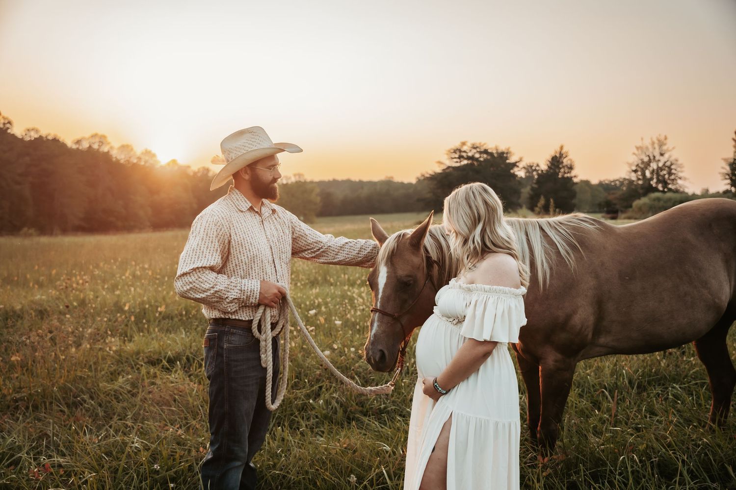 Couple with horse in rustic field during golden hour sunset.