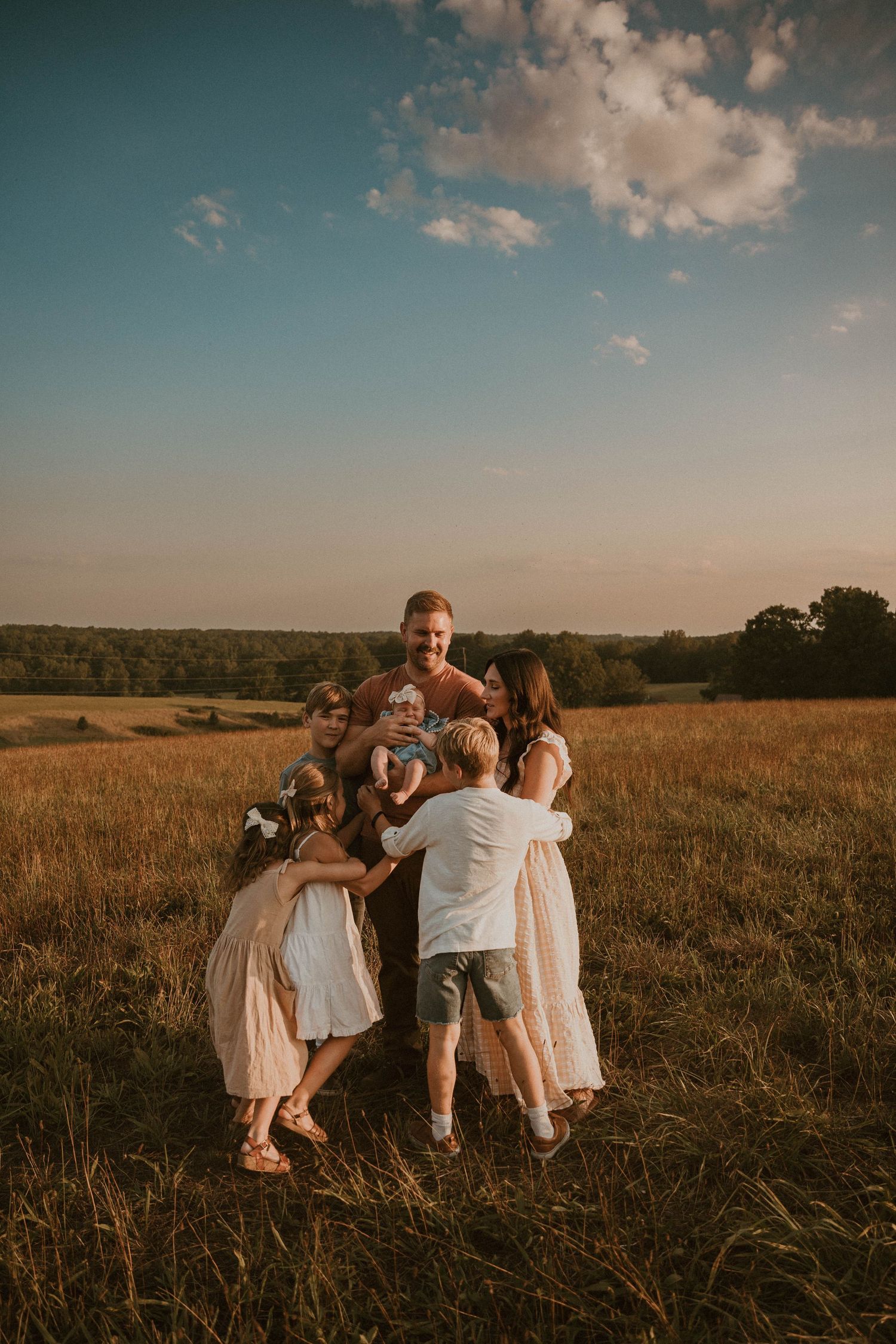 Candid family moment captured in a rustic field at sunset.