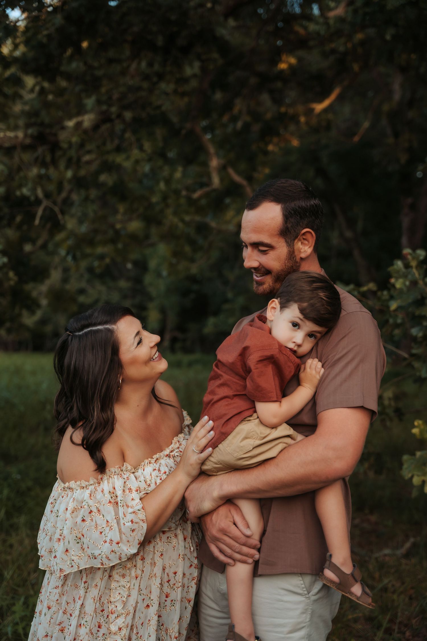 Family photoshoot in a wooded setting during sunset.