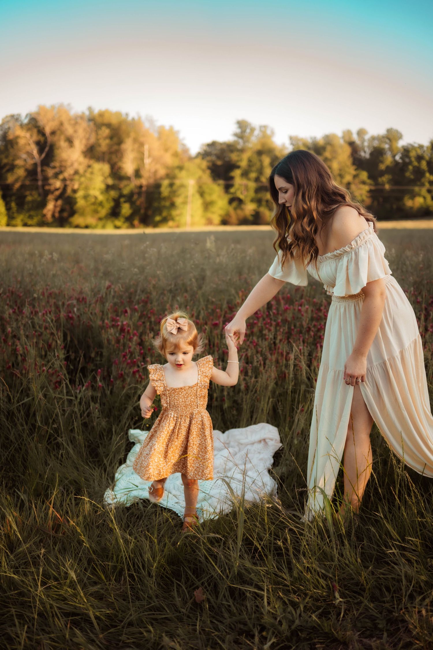 A joyful family photoshoot in a field with tall grass and golden evening light.