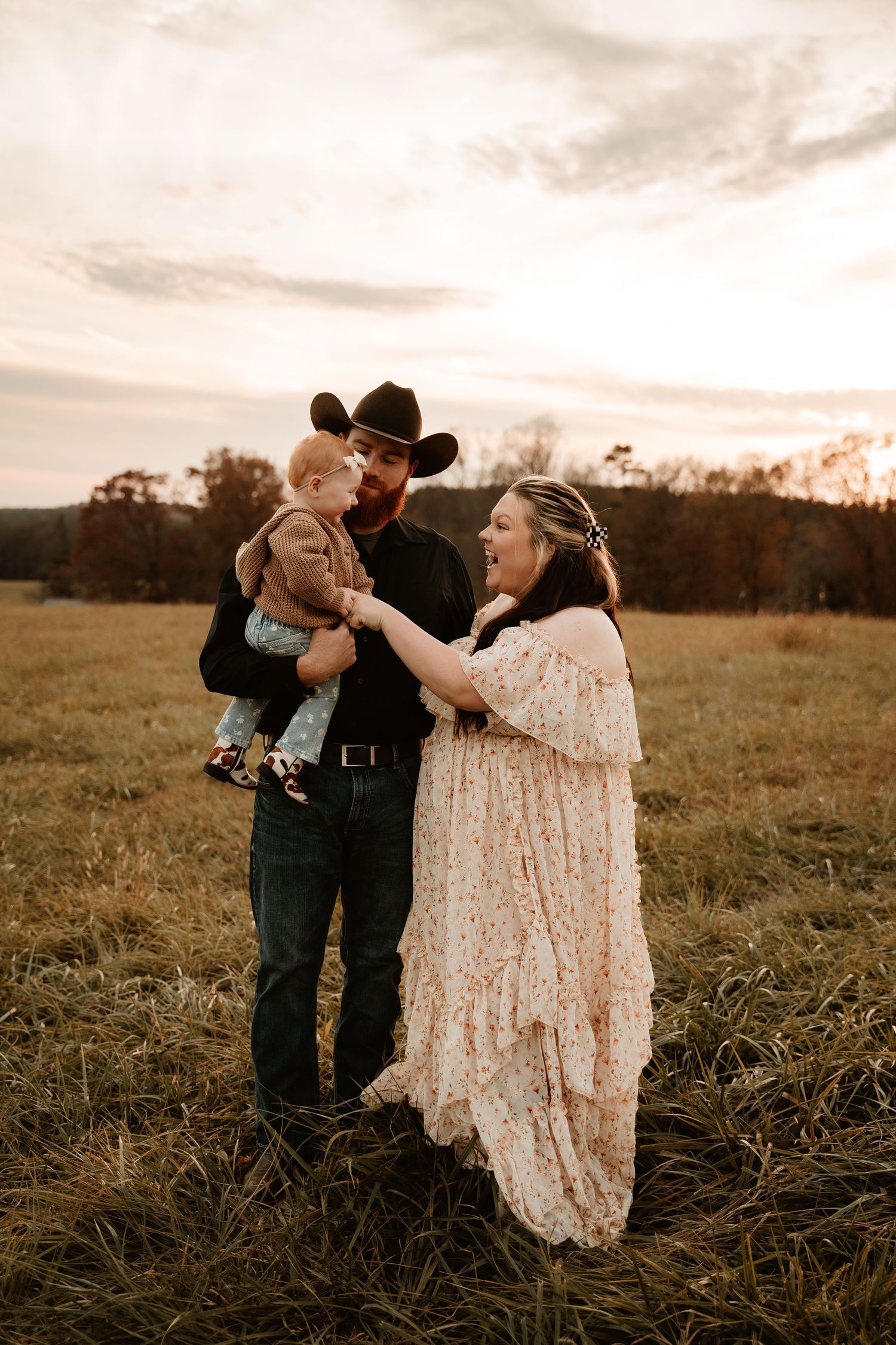 Family photoshoot in a golden field at sunset showing playful interaction.
