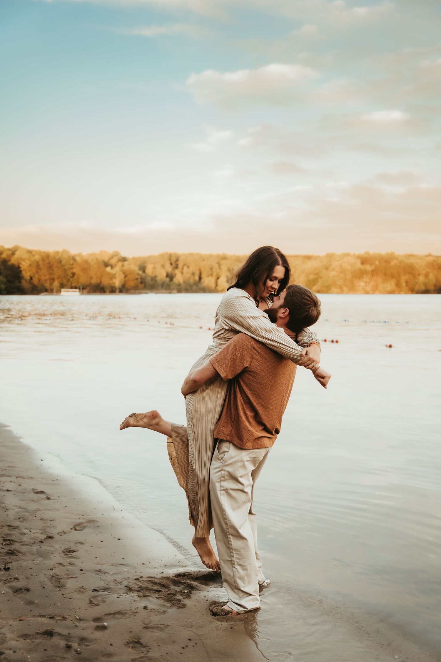Romantic sunset photoshoot at a lakeside beach with warm autumn colors.