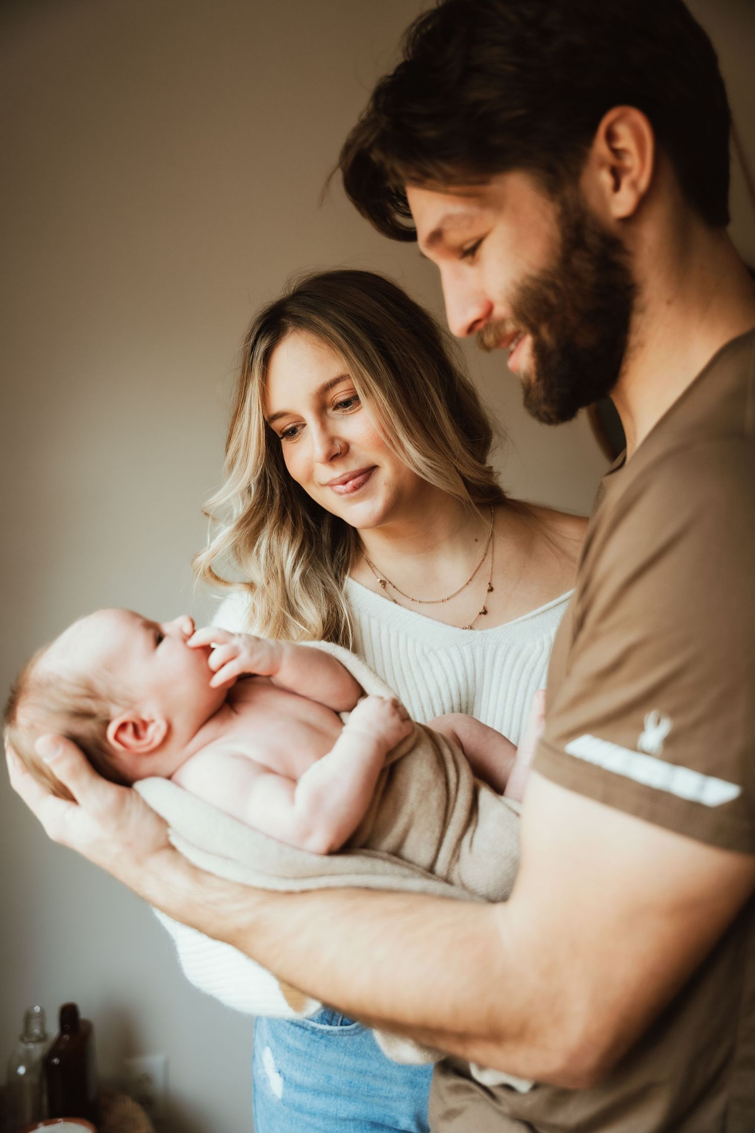 Parents gazing lovingly at their newborn baby in warm indoor lighting.