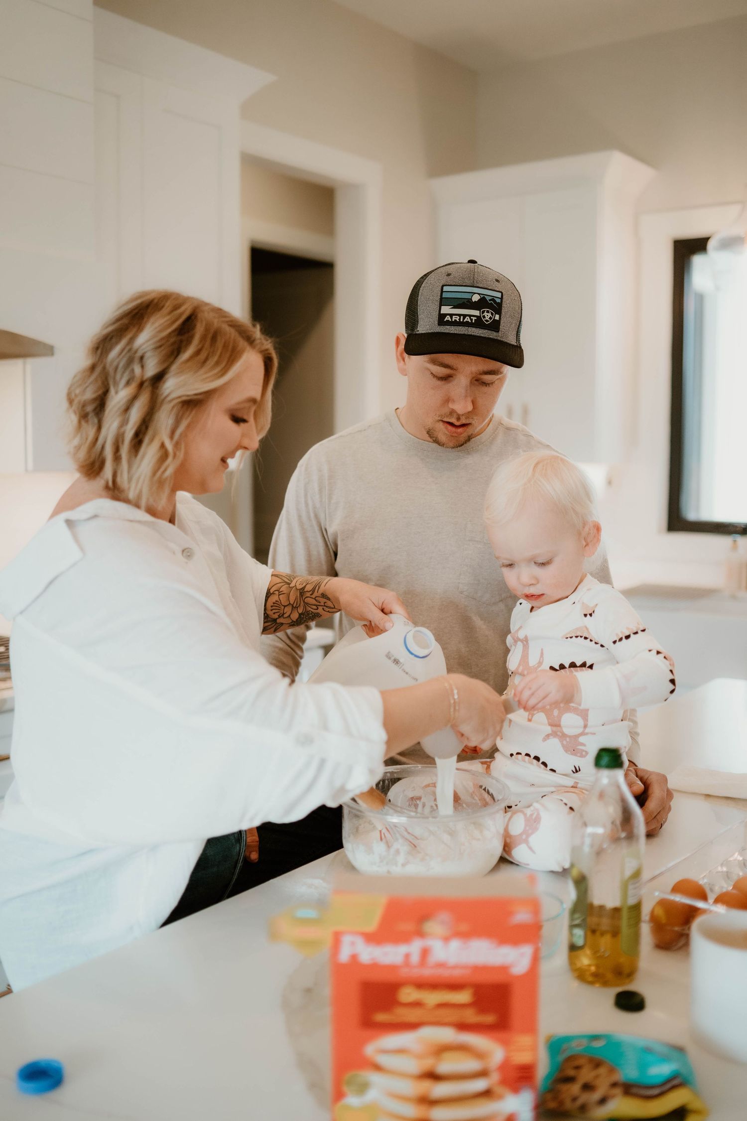 A family makes pancakes together in a bright modern kitchen.