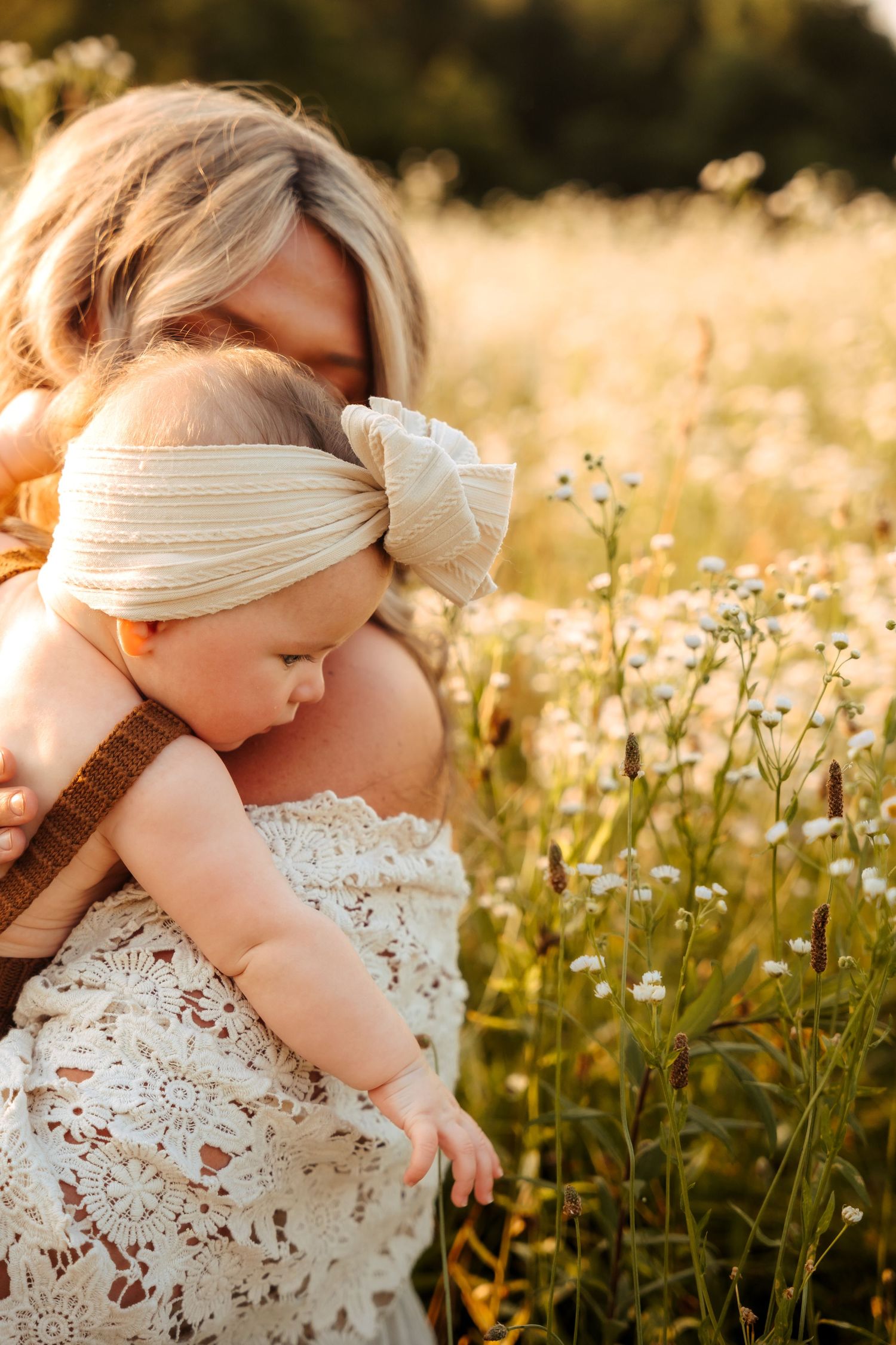 Young child in white dress exploring wildflower field during golden hour.