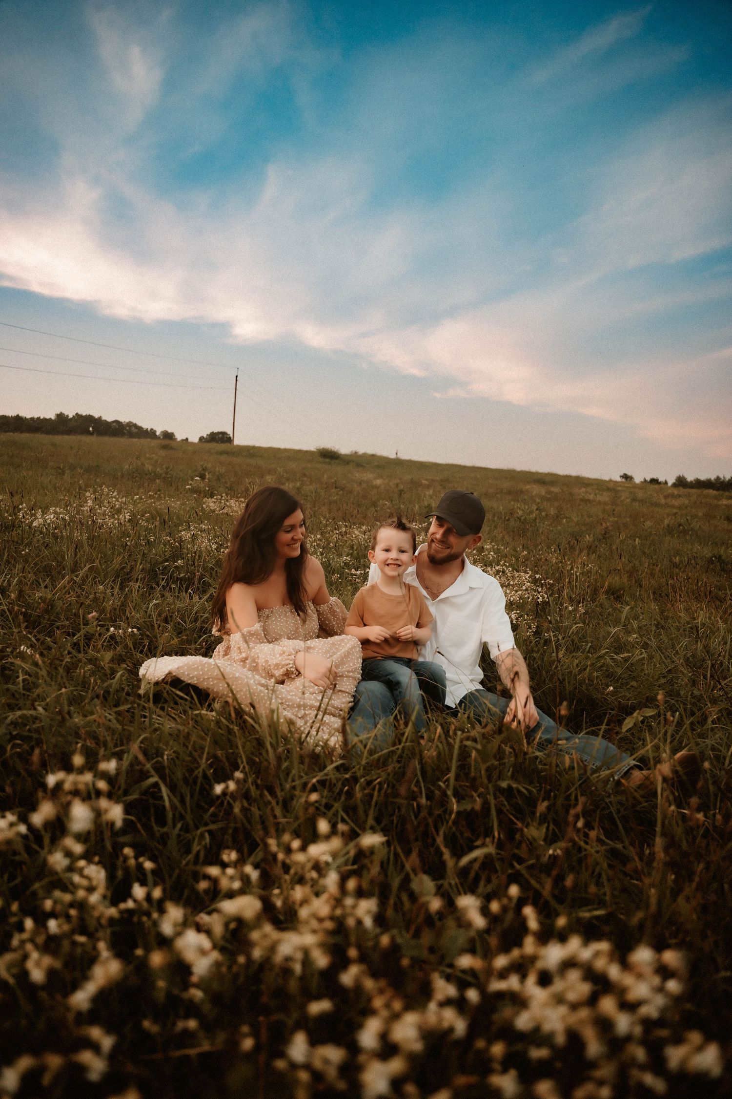 Couple relaxing in a wildflower meadow under blue skies during sunset.