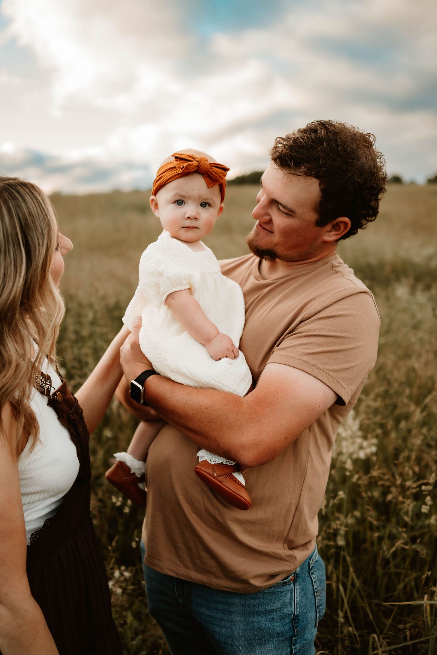 A family shares tender moments together in a golden field at sunset.