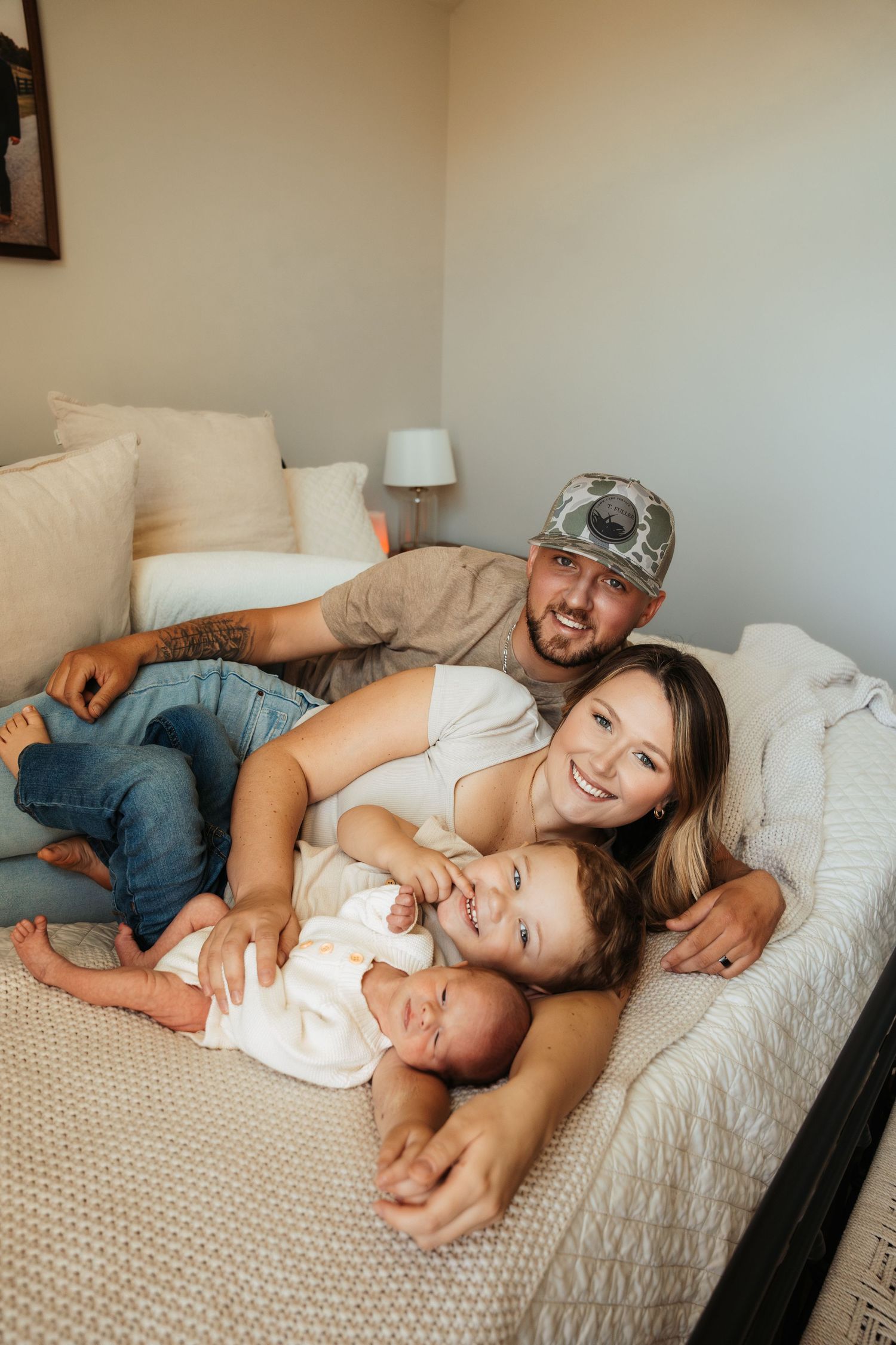 Candid family moment captured on white bed showing joyful expressions and casual attire.