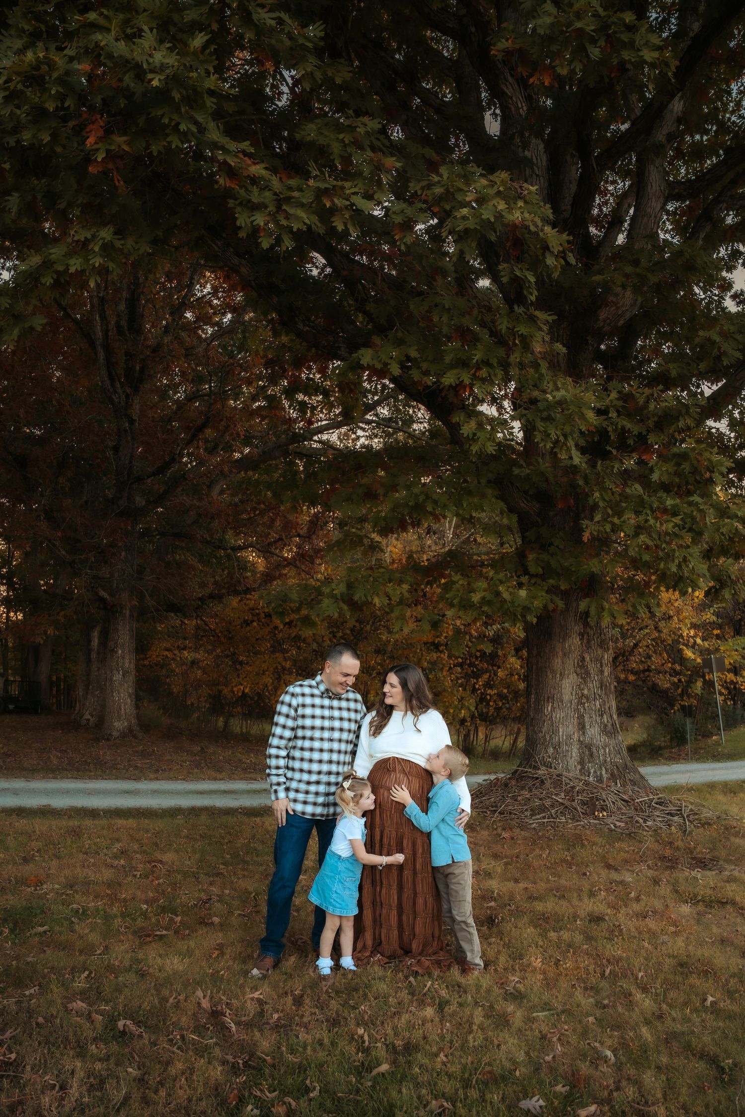 Family walking together through autumn trees at sunset in park setting.
