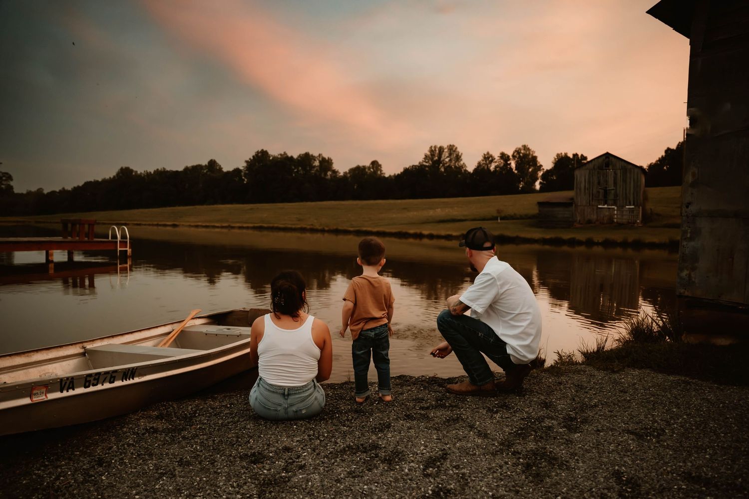 Peaceful lakeside scene with boat dock and rustic buildings at dusk.