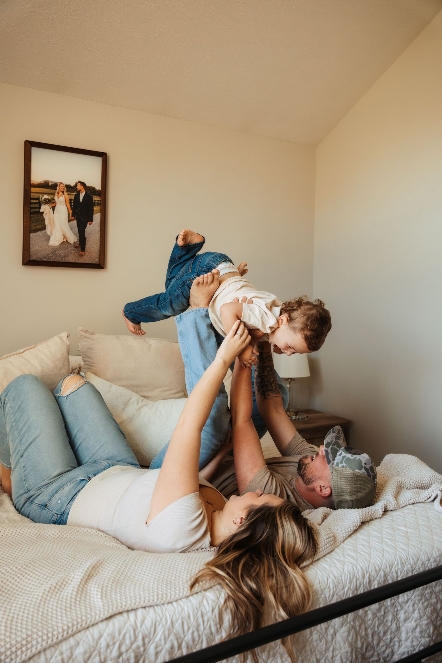 Playful lifestyle photos of family bonding on white bedding in natural light.