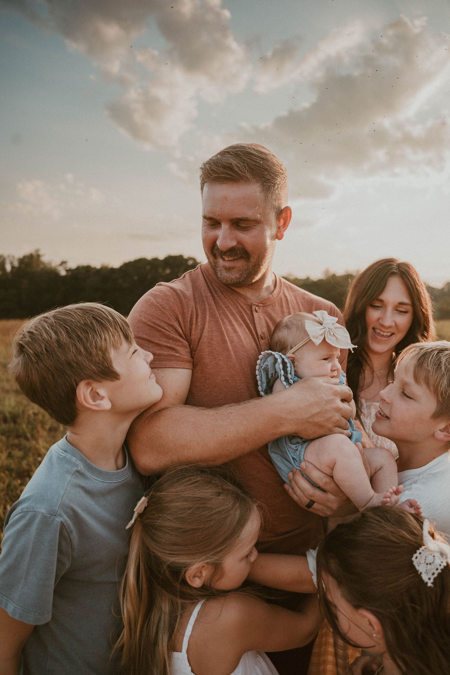 Intimate family gathering captured during golden hour in a meadow.