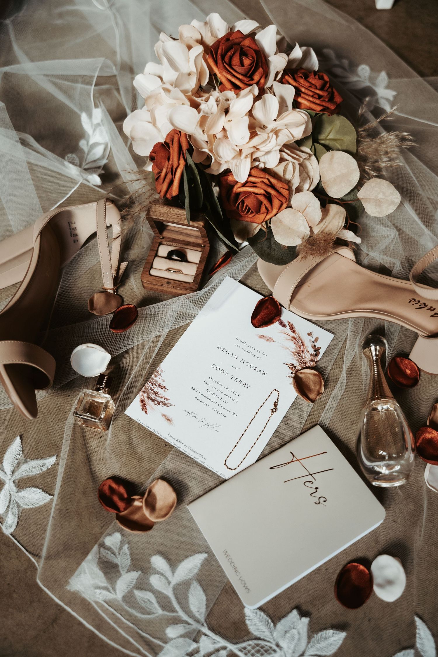Wedding details flatlay with invitation, flowers, and decor in muted tones and copper accents.