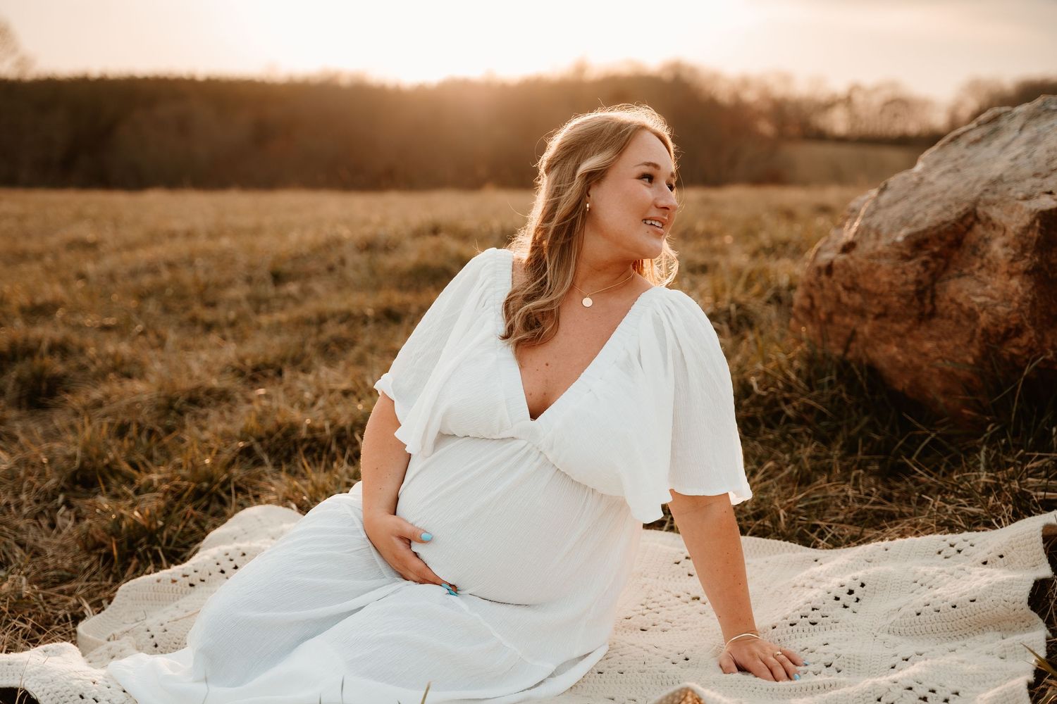 Ethereal maternity photos in a white dress during golden hour.