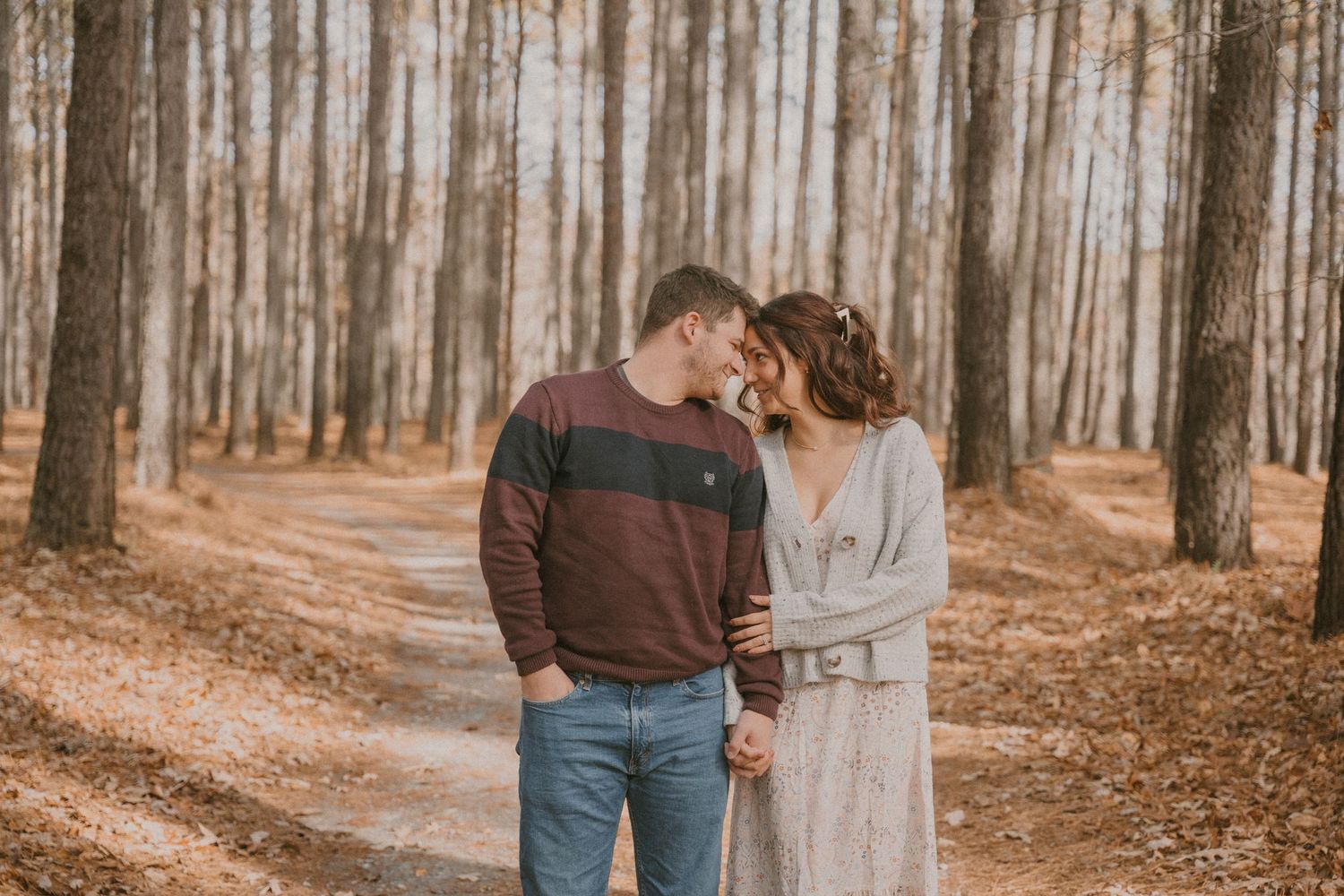 A romantic autumn forest photoshoot with a couple in casual attire.