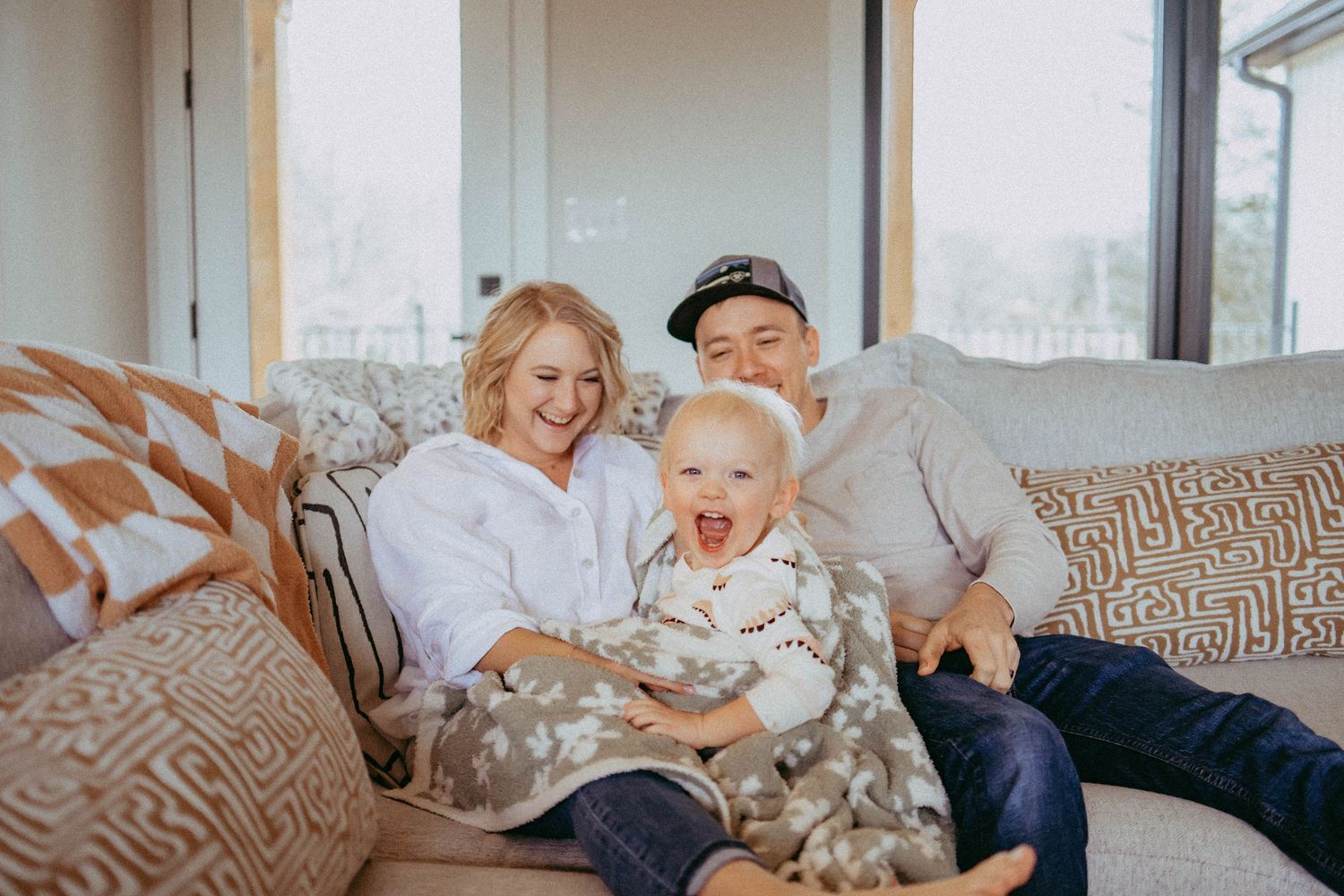 Candid moments of family playtime on a cozy gray couch.