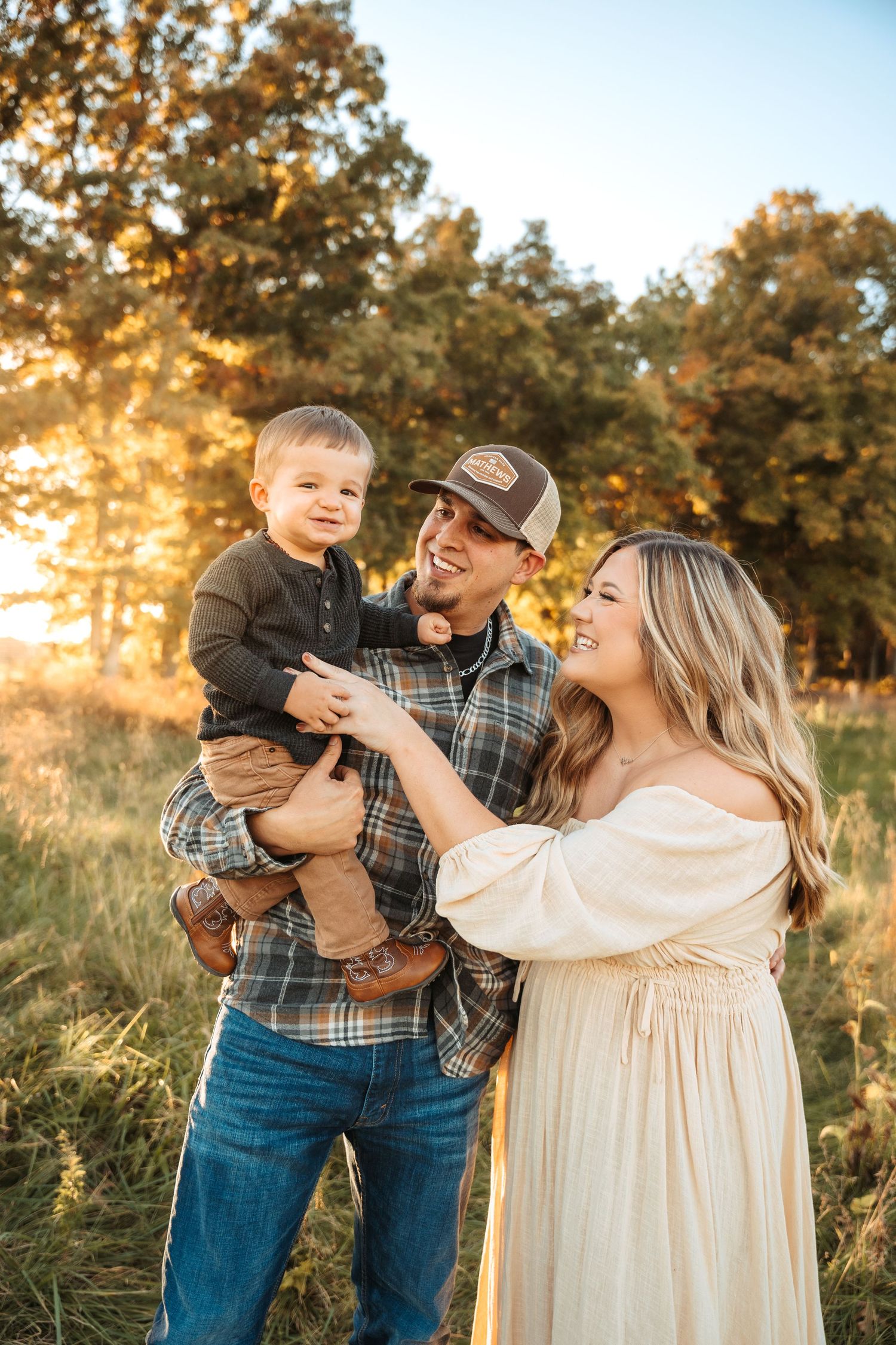 Family sharing joyful moments together during fall photoshoot with golden trees in background.