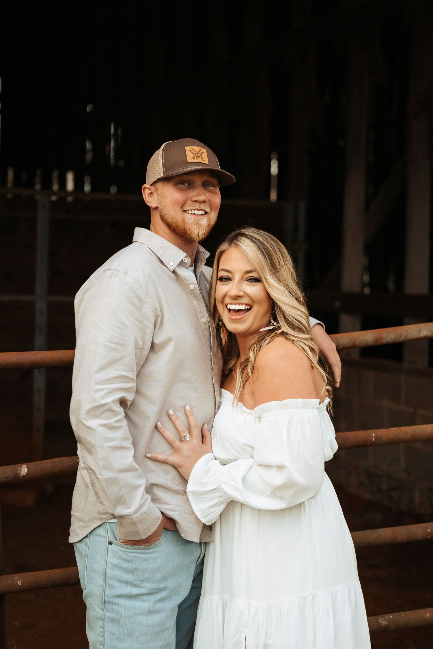 A casual couples photoshoot inside a rustic wooden barn setting.