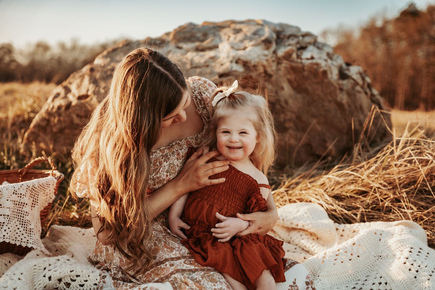 Mother and child in rustic outdoor setting with autumn colors and blanket.