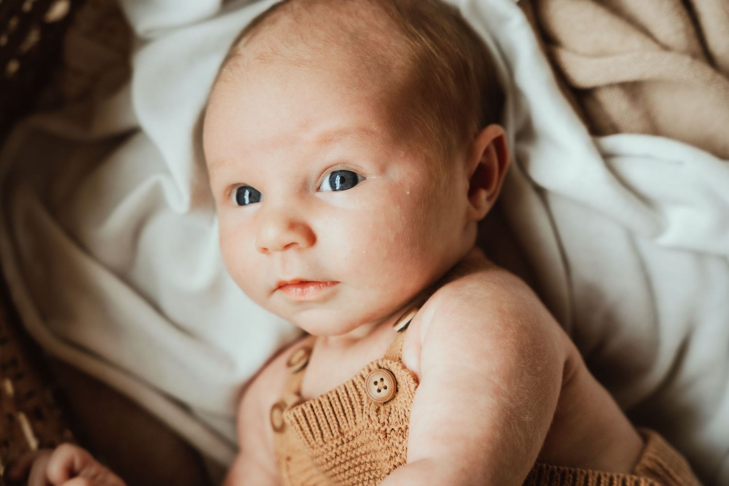Close up of baby with temporary tattoo lying on white fabric.