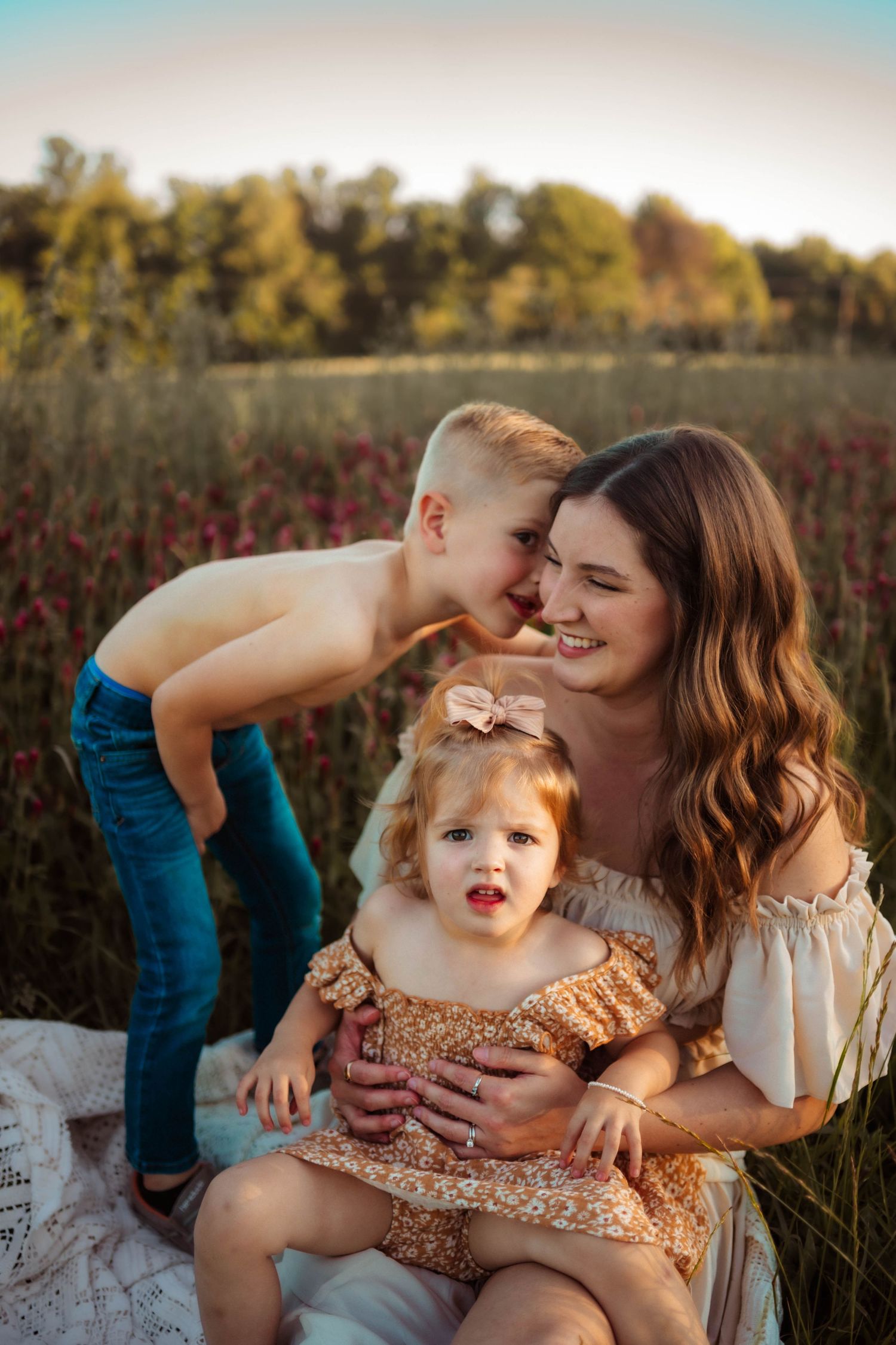 A tender family moment captured in a field during golden hour with warm autumn colors.