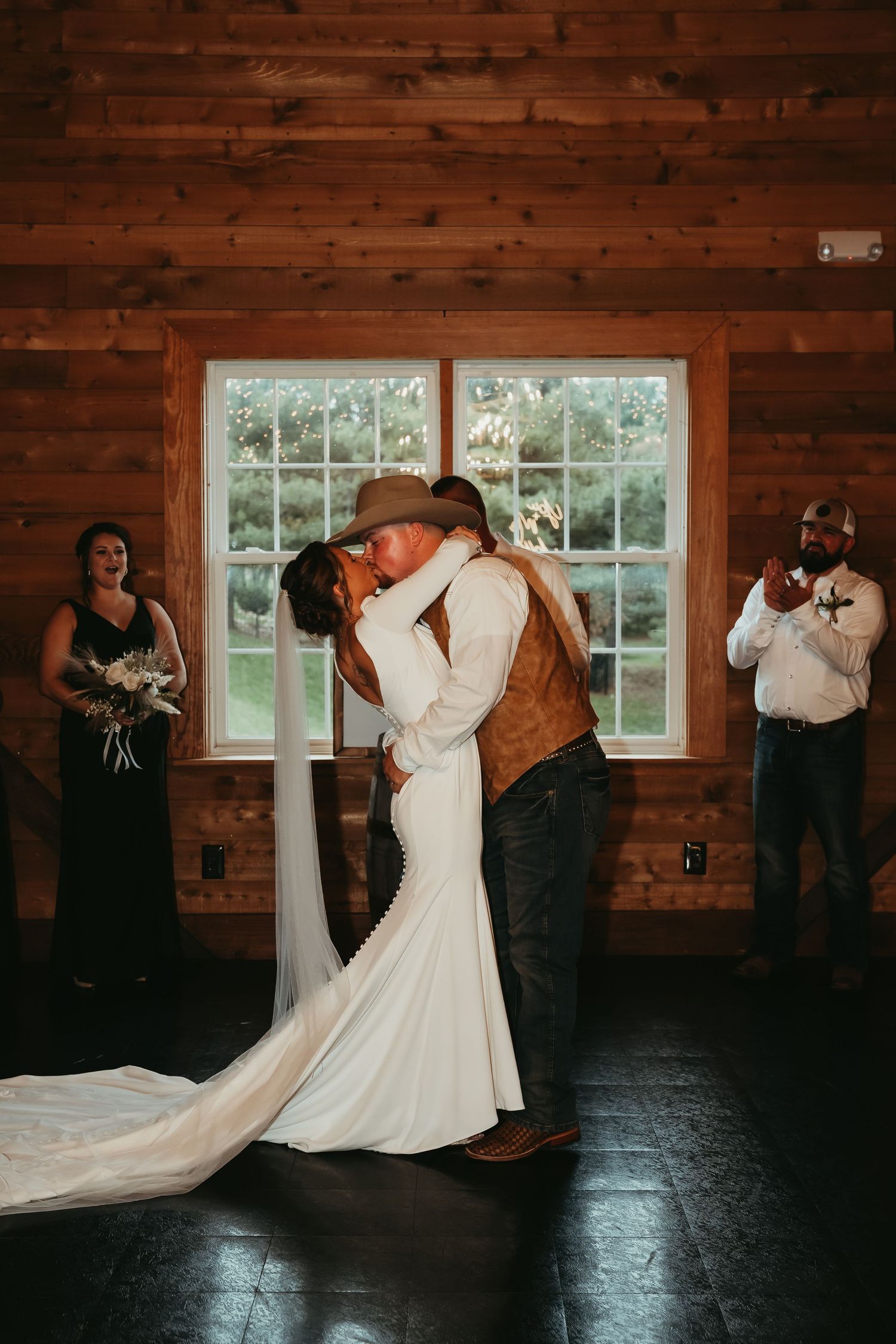 Couple dancing in rustic wooden barn venue with long white wedding dress.