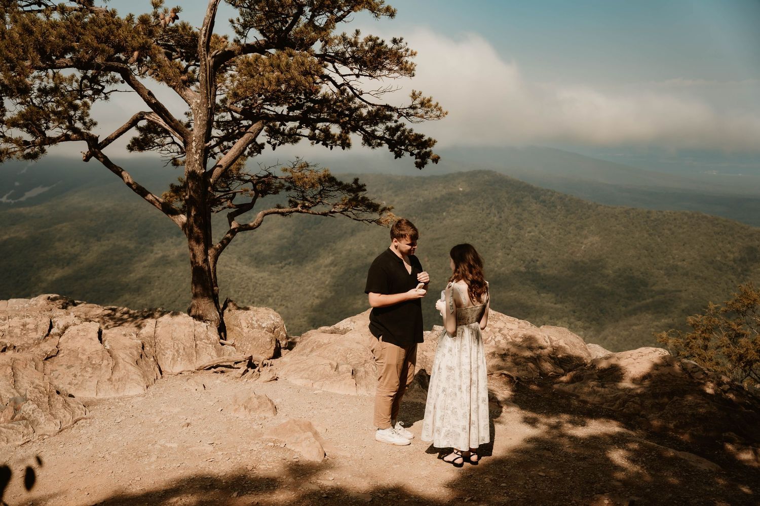 A scenic mountain overlook with dramatic views of rolling hills in the distance.
