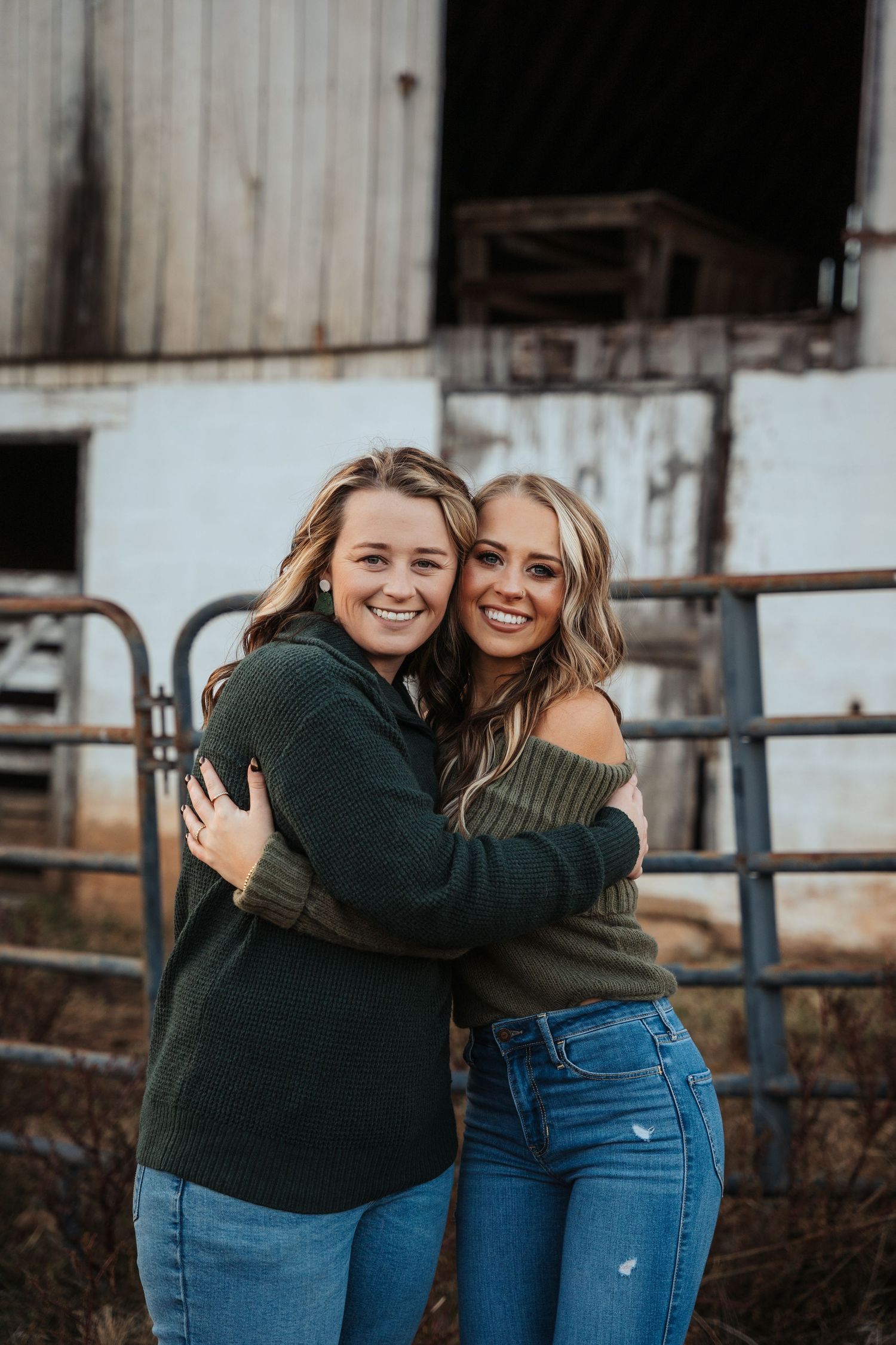 Friends sharing joyful embrace outside rustic barn setting.