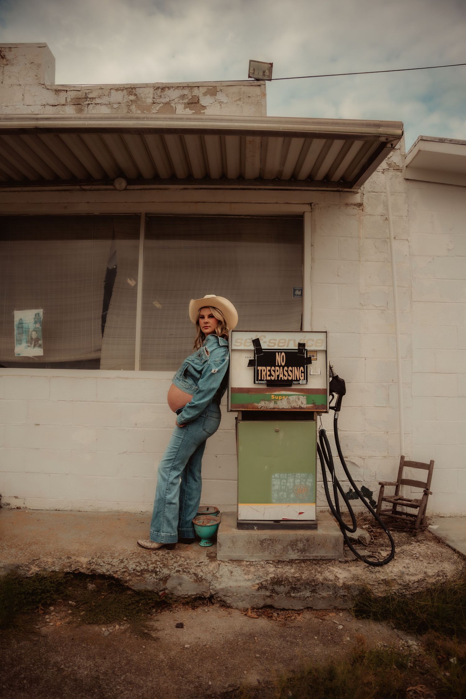 Vintage-style photoshoot at abandoned rural building with rustic props and signage.