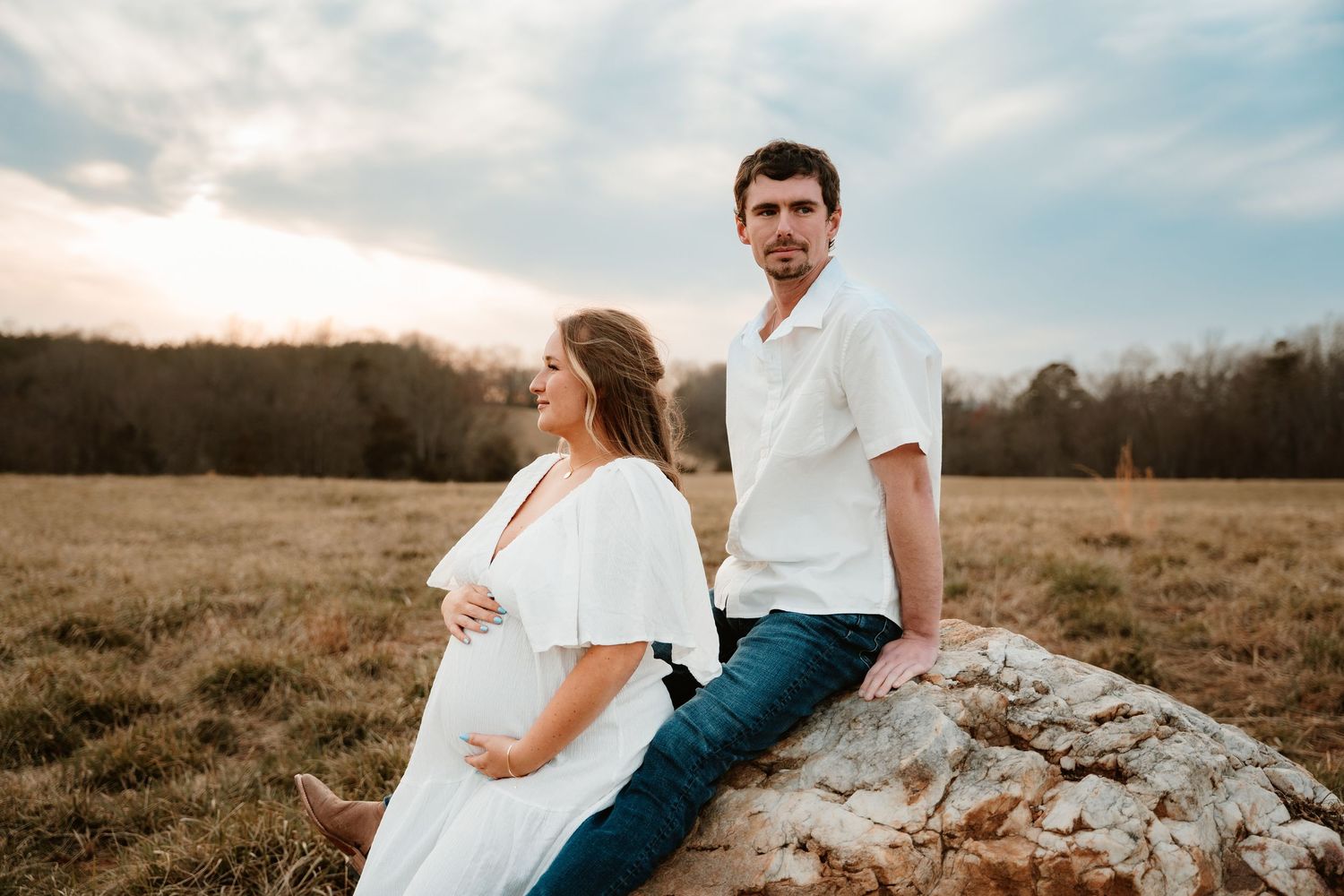 Romantic outdoor maternity session in a rustic field at sunset.
