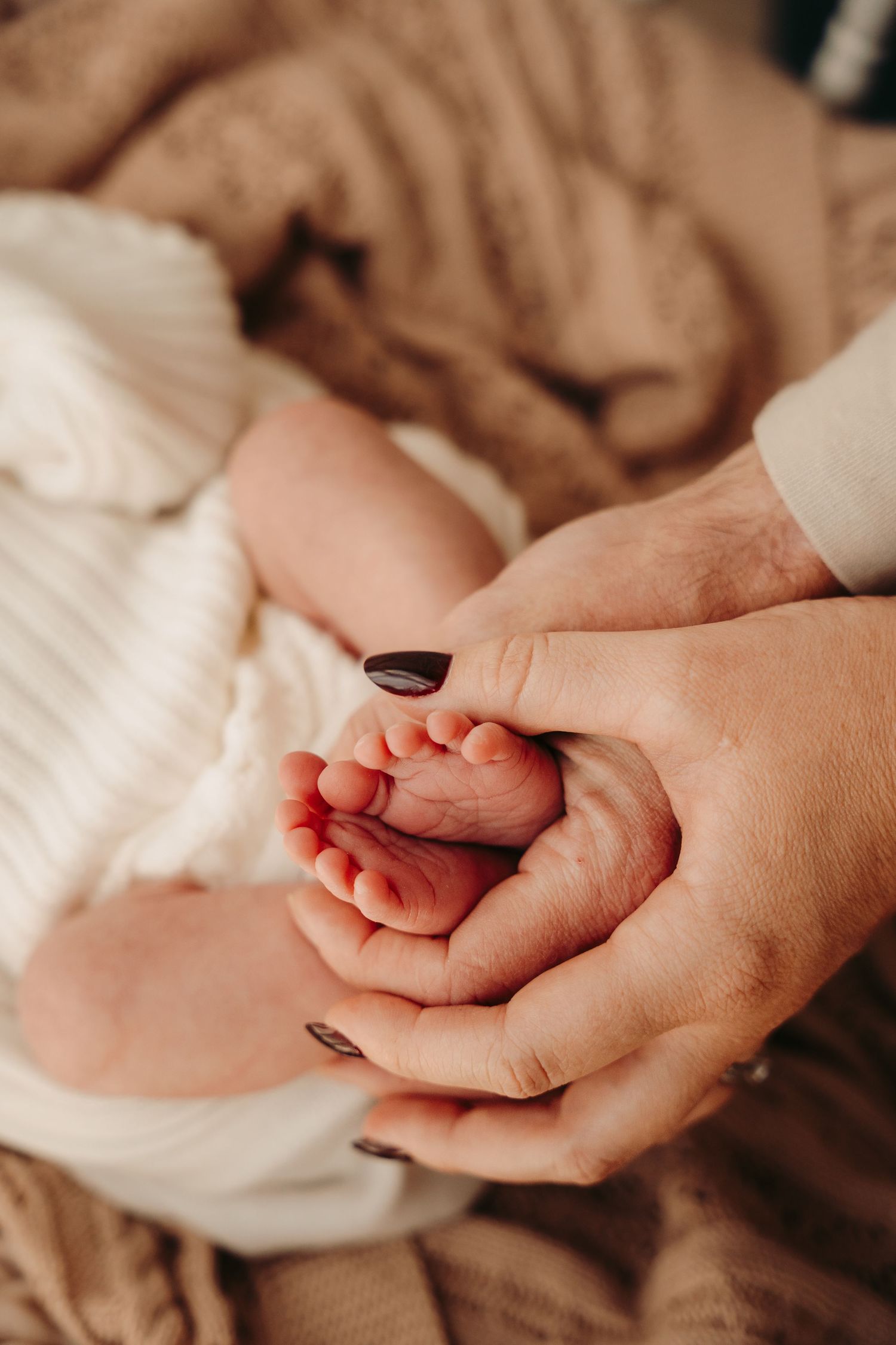 Close-up shots of tiny baby hands being held gently against white fabric.