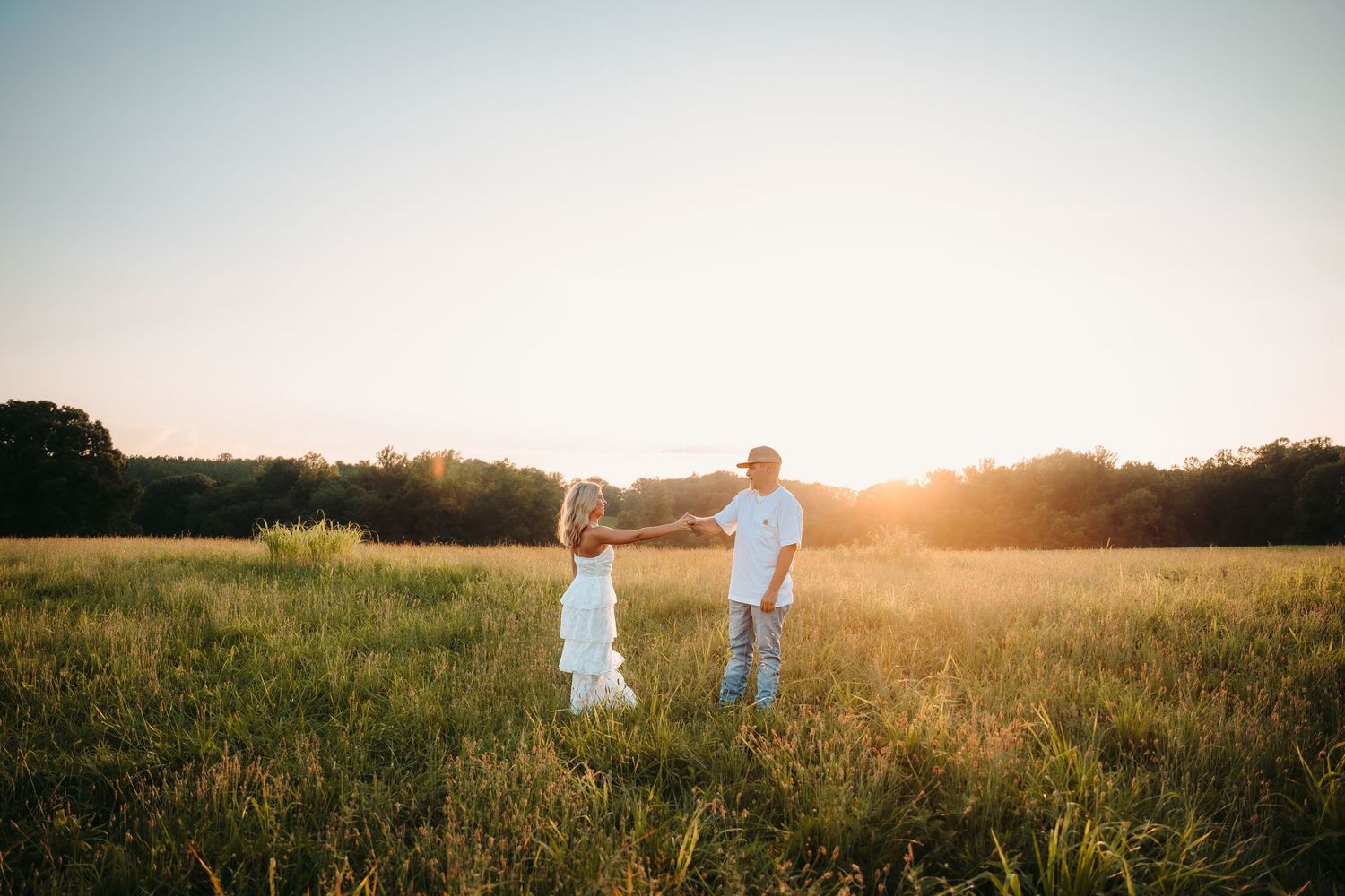 A scenic meadow landscape at golden hour with long grass and distant trees.