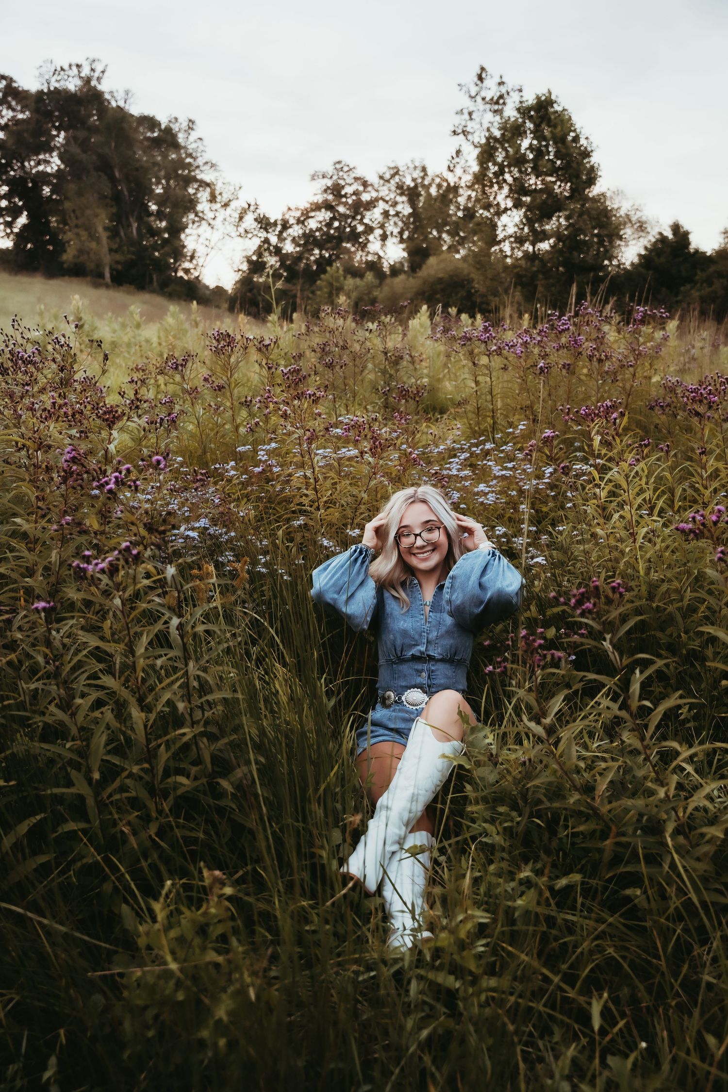 Person relaxing in field of purple wildflowers during golden hour.