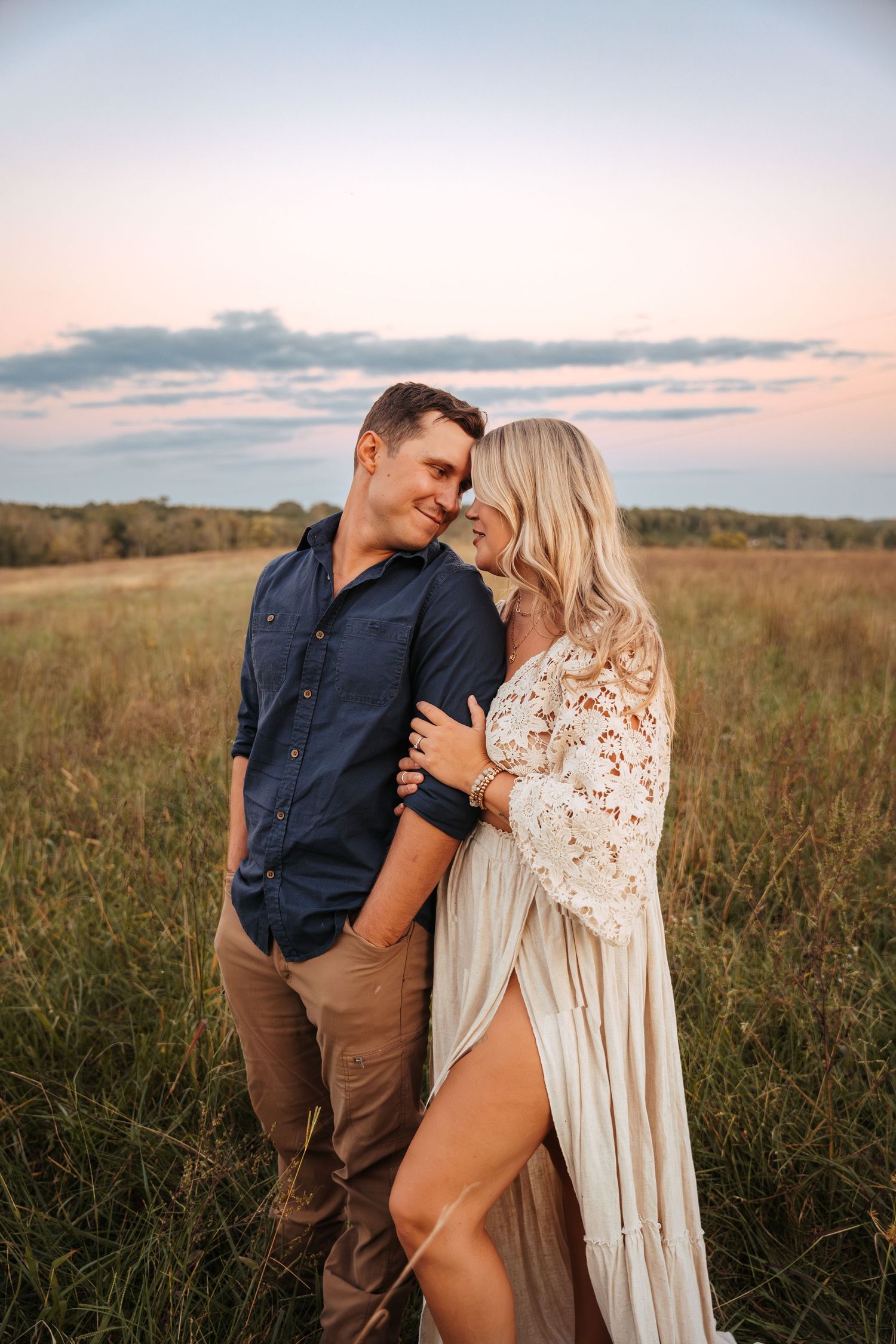Romantic couple photoshoot in a rustic field during golden hour.