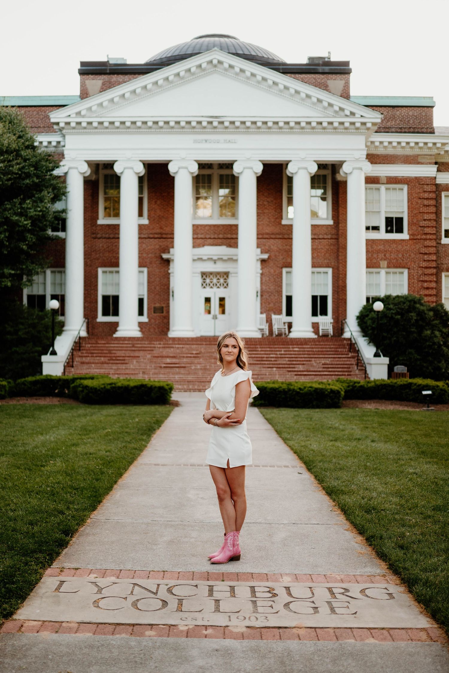 Classic brick college building with white columns serves as backdrop for outdoor portrait session.