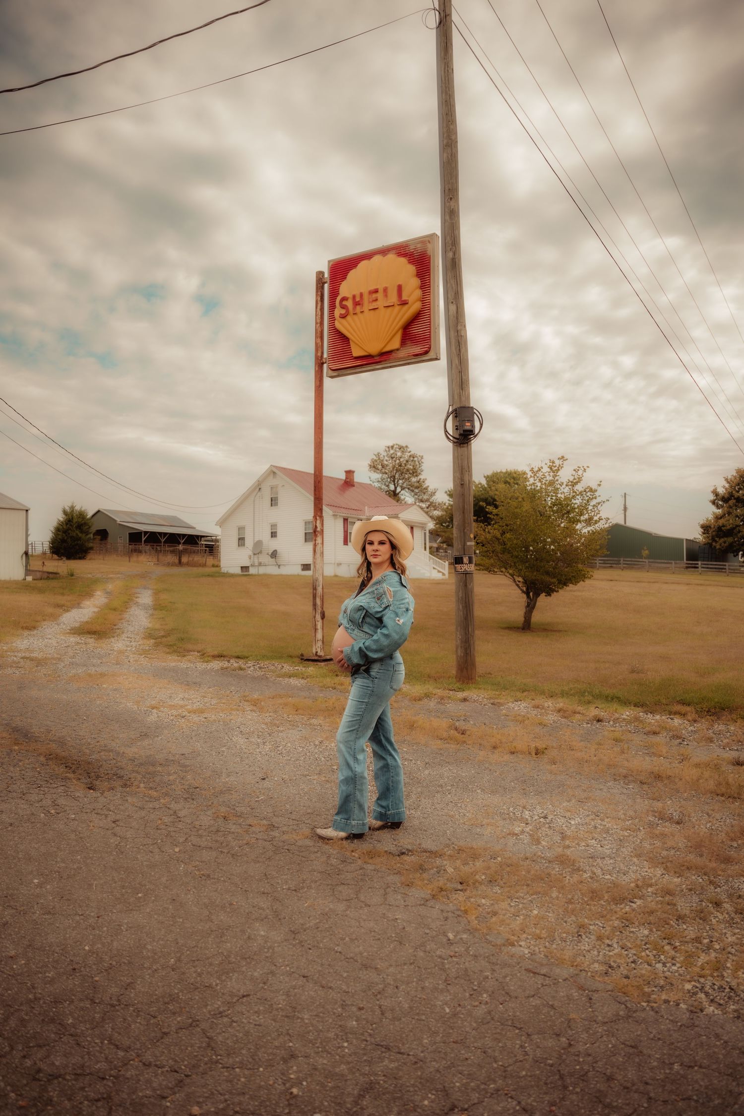 Retro-themed photoshoot near old gas station signs with dramatic cloudy sky.