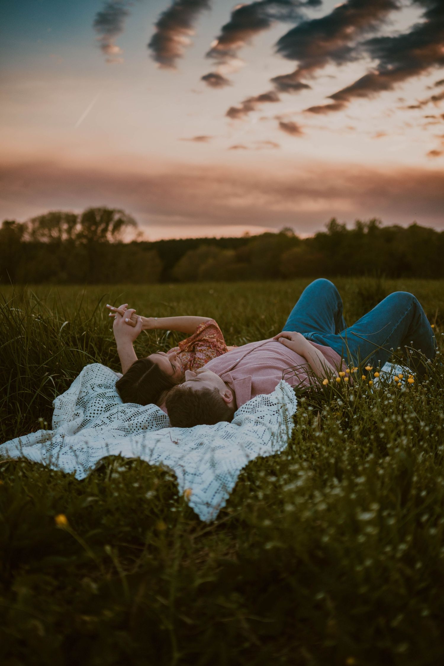 A dreamy sunset photo of someone lying in a wildflower meadow.