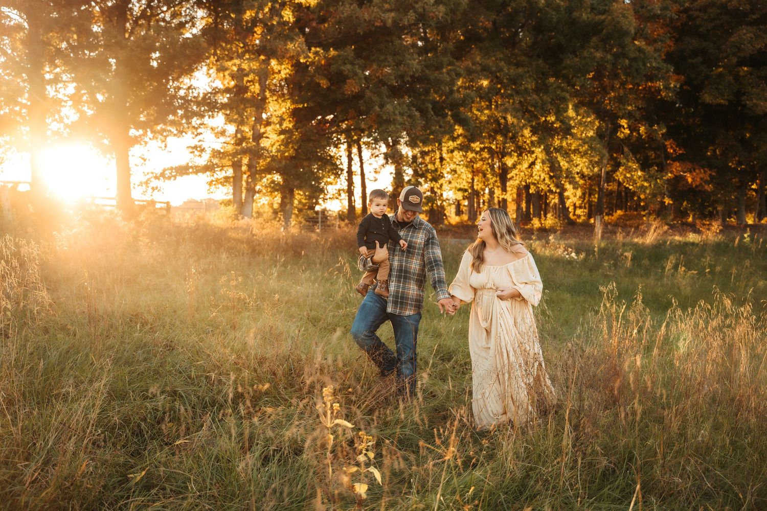 Golden sunlight filters through trees in a dreamy outdoor photoshoot setting at sunset.