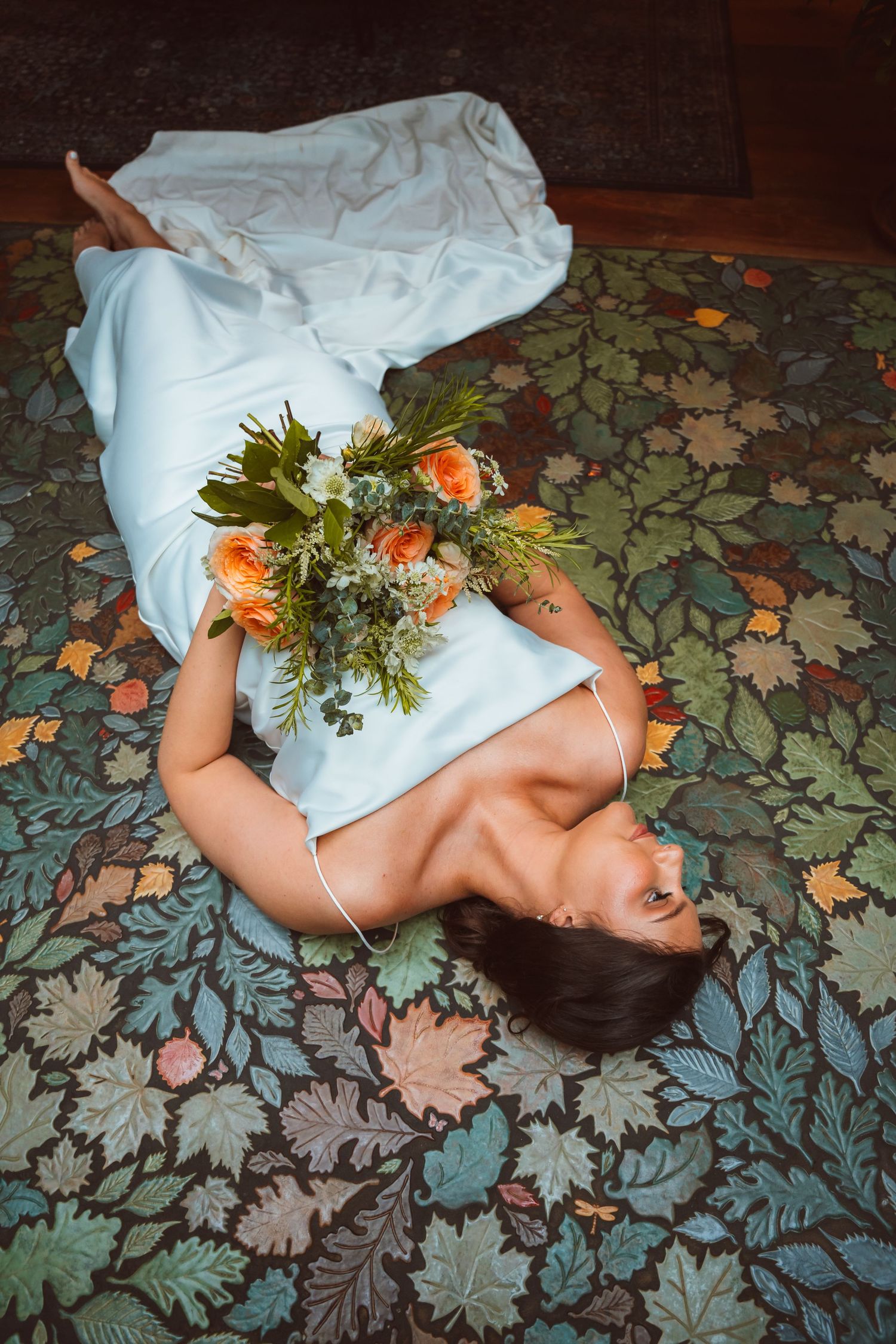 Artistic portrait with orange flowers and greenery against a floral patterned background.